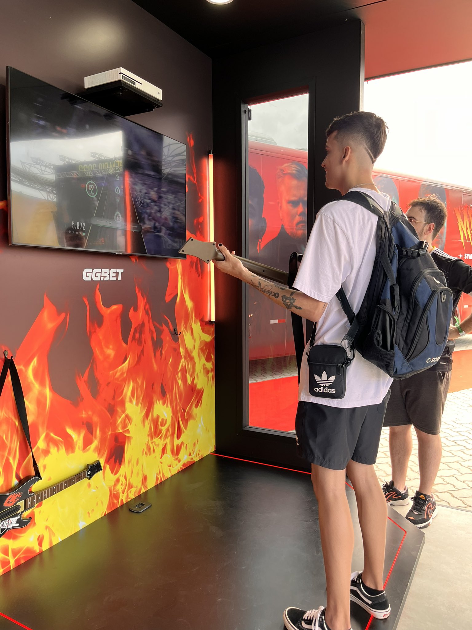 Visuel du projet Metality : Jeune homme blanc vu de dos avec un sac à dos, jouant à un jeu de simulation de guitare.