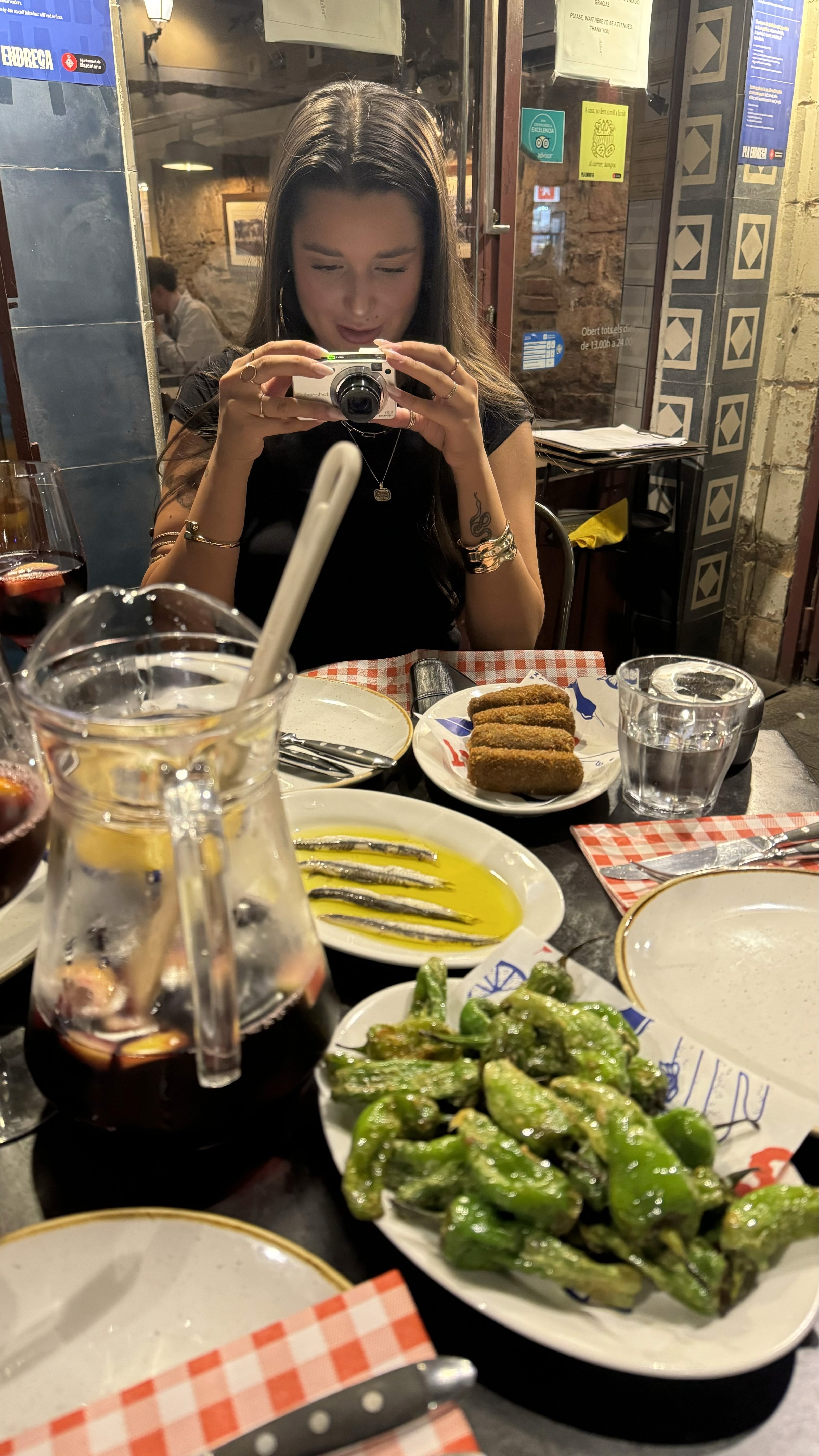 A view from an airplane window shows the aircraft's wing with a golden hue reflecting the setting sun, against a serene backdrop of fluffy clouds and a clear sky.