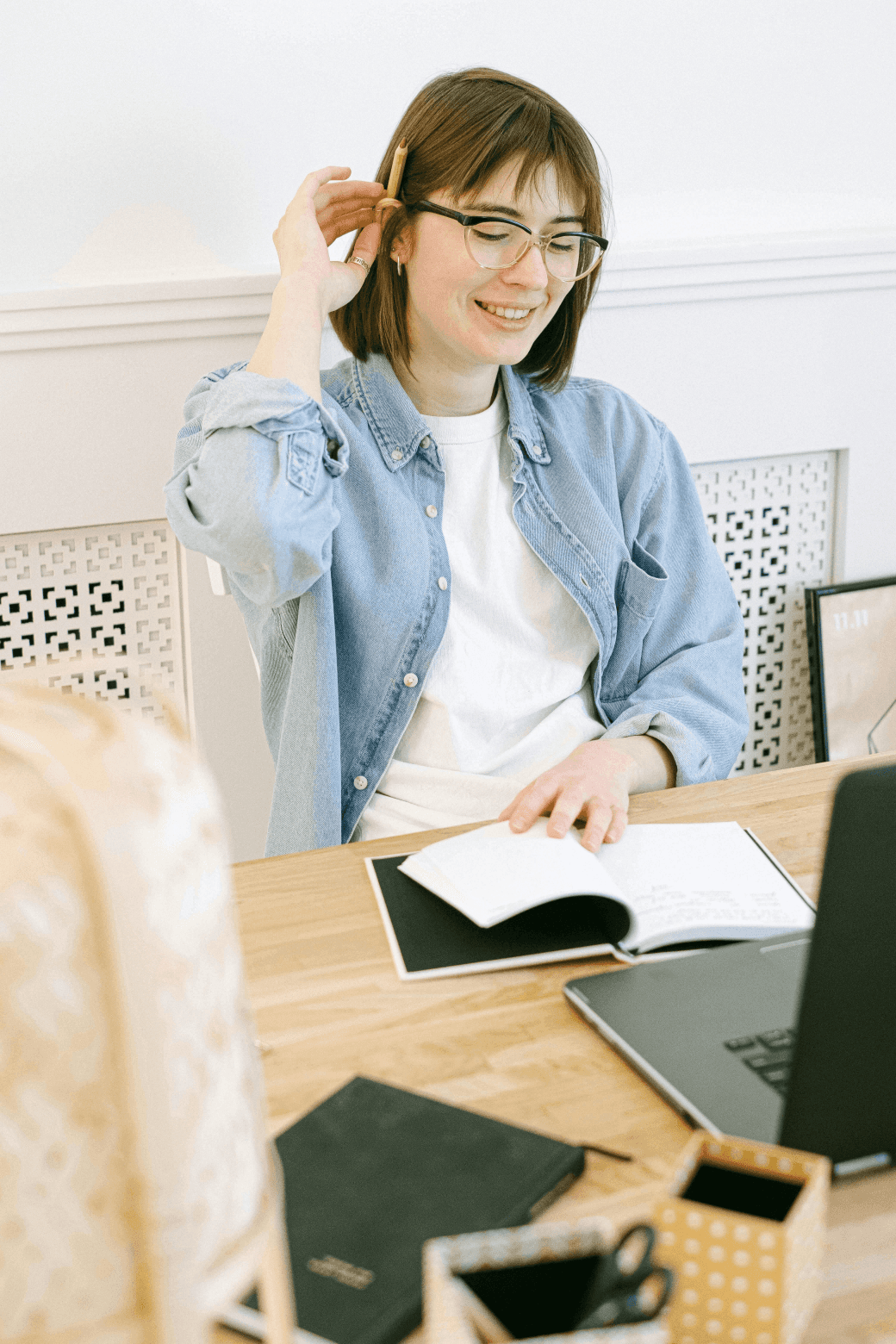 Lady writing in a notepad with a laptop on front of her