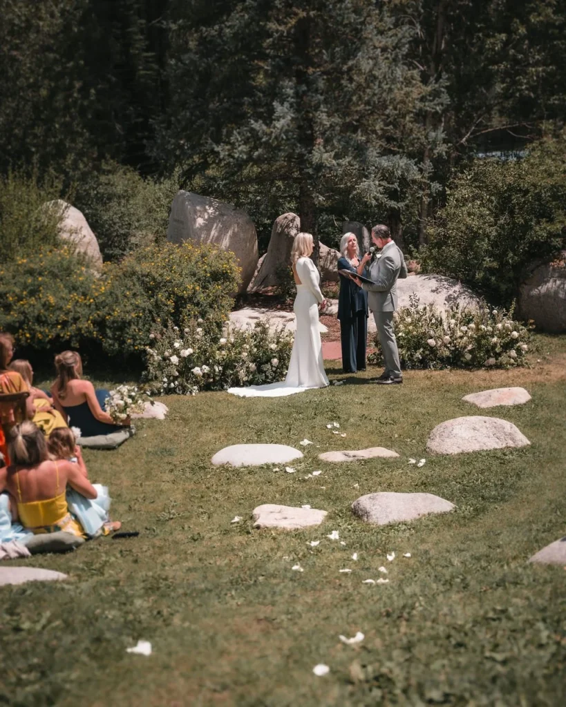 Outdoor wedding ceremony viewed across a garden lawn