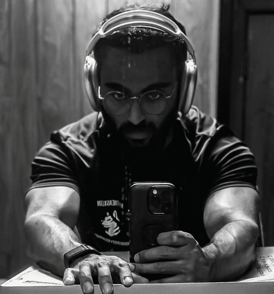 A close-up of a person wearing green-tinted glasses, with a serious expression and smooth skin.