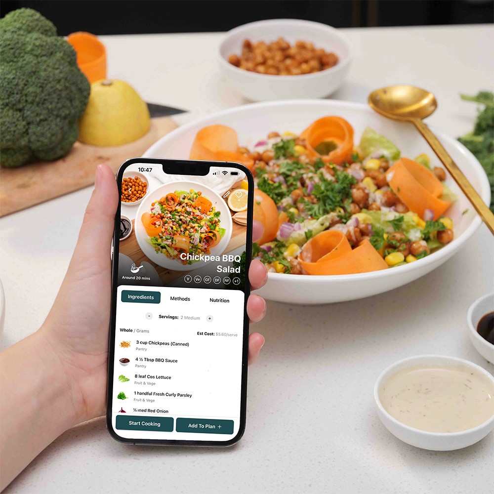 Person Holding Phone - Nourish App with recipe in background