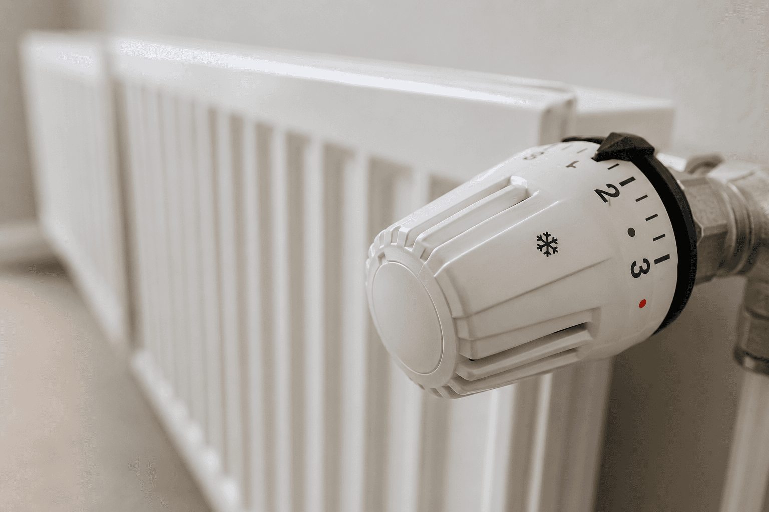 Thermostatic radiator valve fitted to a white panel radiator in a UK home connected to an air source heat pump system