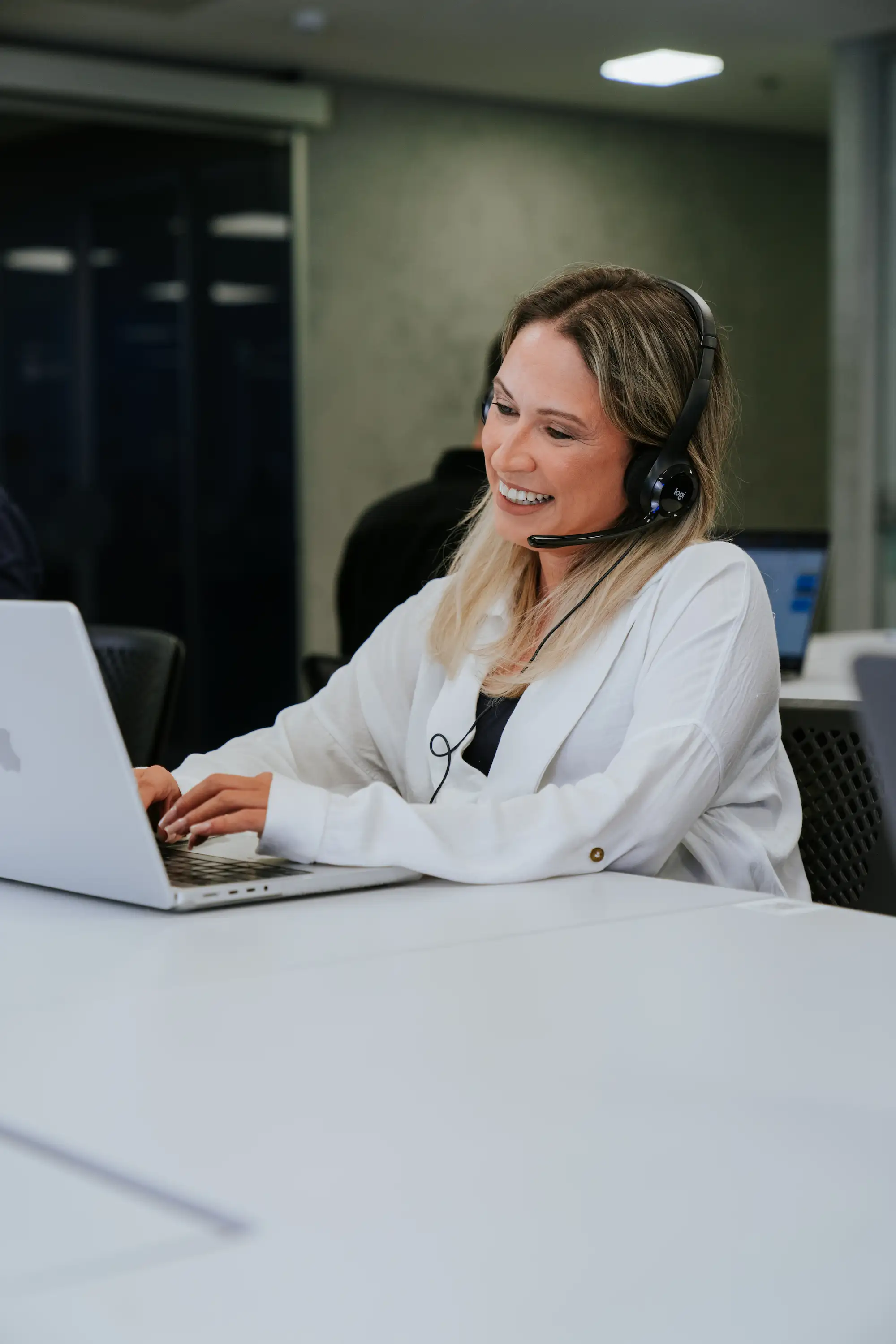 Duas pessoas em um escritório moderno analisando a situação fiscal no computador, com gráficos de desempenho ao fundo, garantindo a conformidade da empresa.