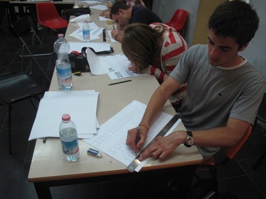 A photo of a student using a crayon and ruler on a piece of paper.