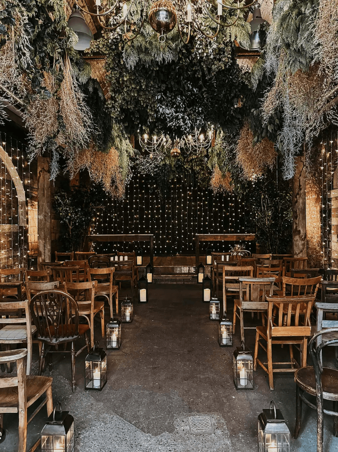 The Old Timber Store with lush hanging foliage, chandeliers, candles, and wooden chairs