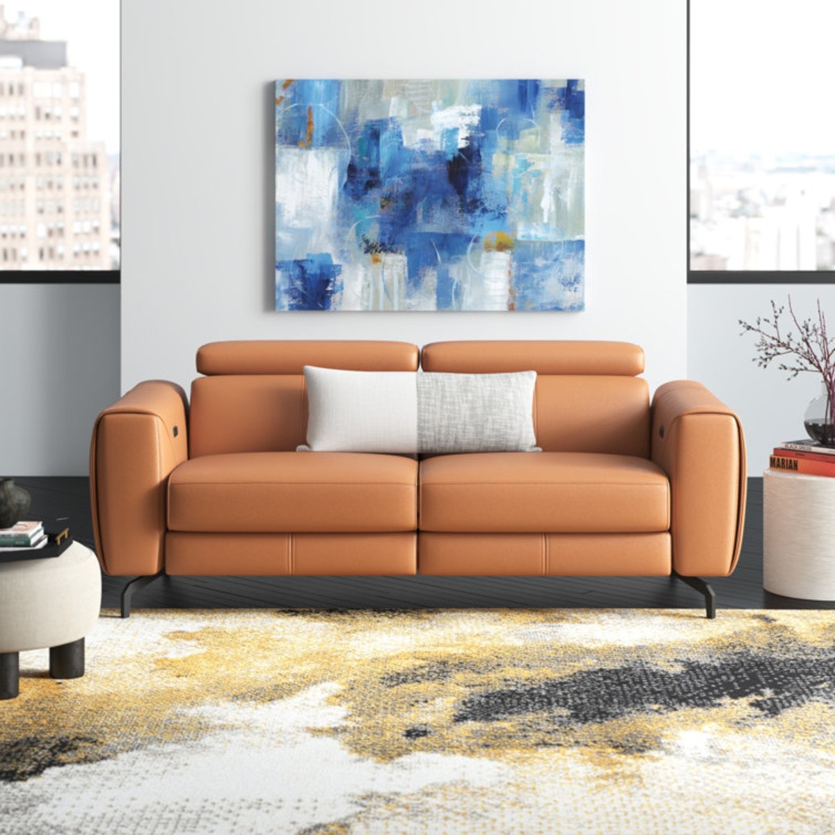 Tan leather reclining loveseat with adjustable headrests, set in a modern living room with abstract decor and large windows.