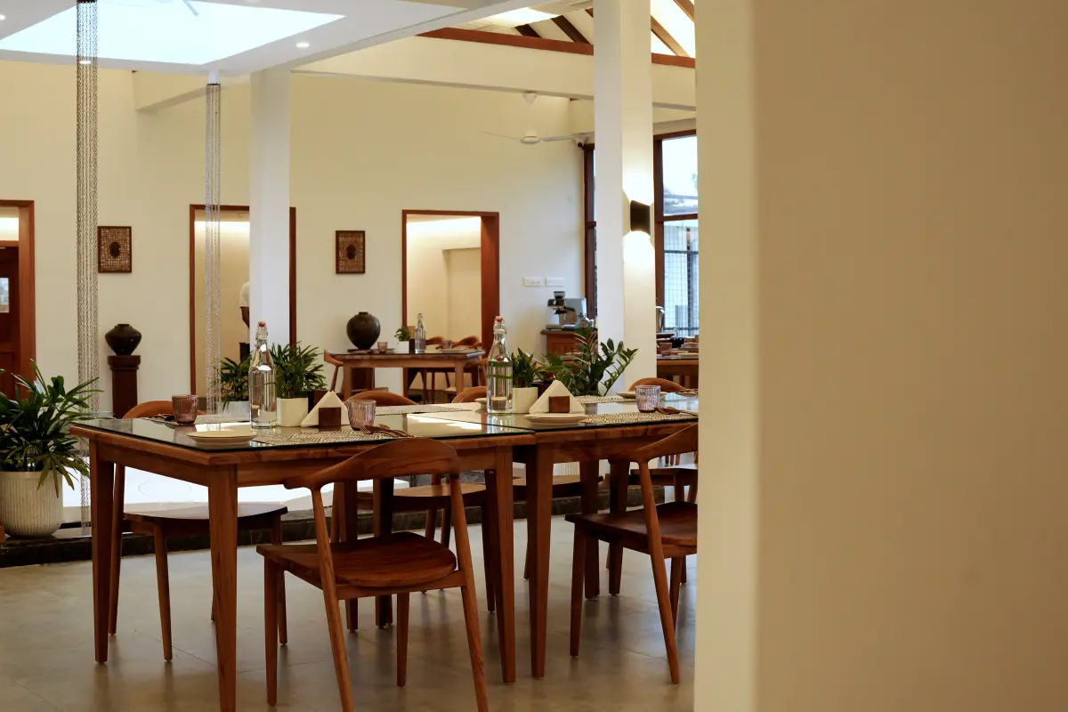 Indoor dining hall at Vedic Village Alleppey set with wooden tables for a wedding meal, natural light through skylights