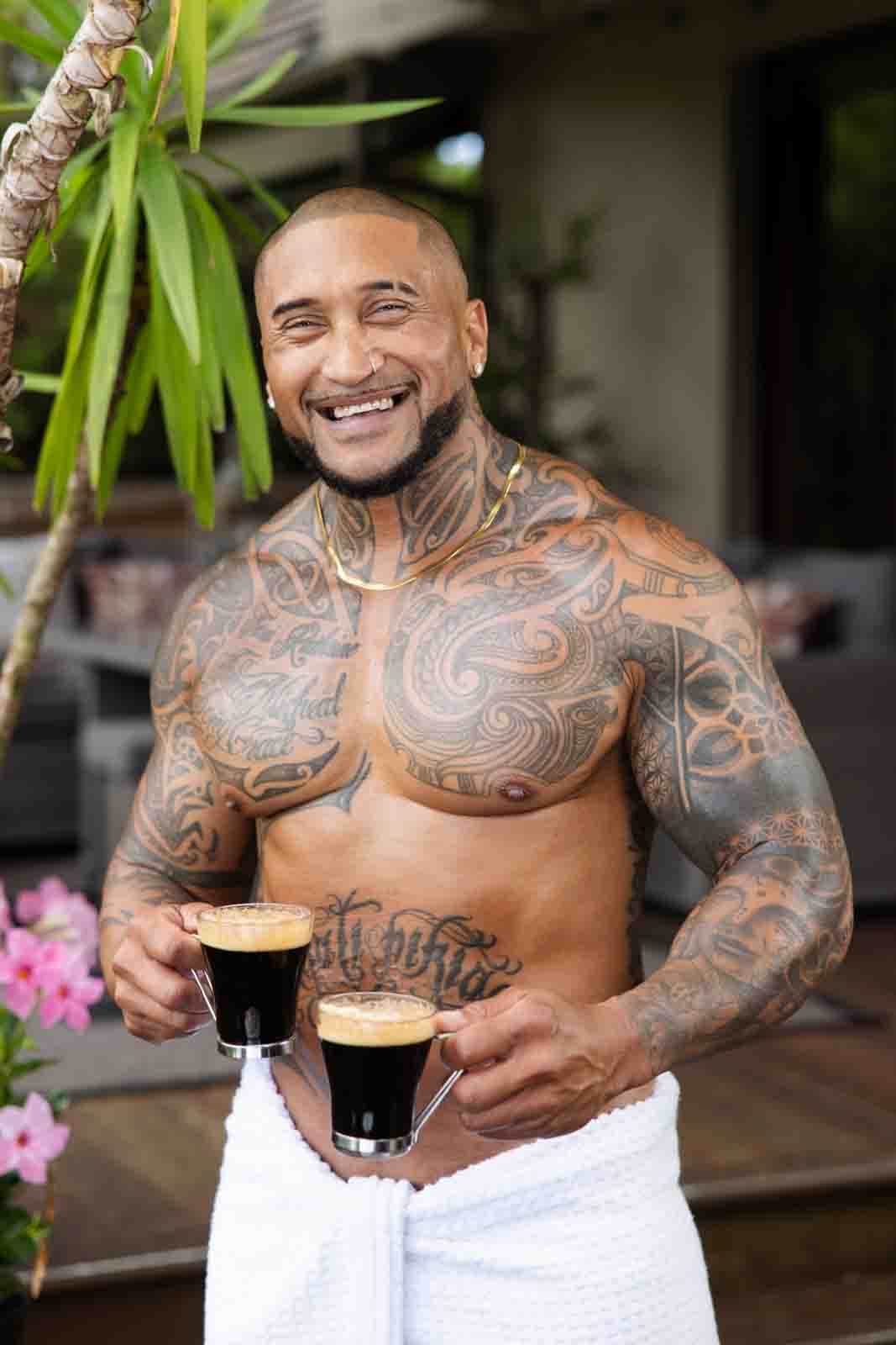 Man with towel wrapped around waist holding two espresso coffees