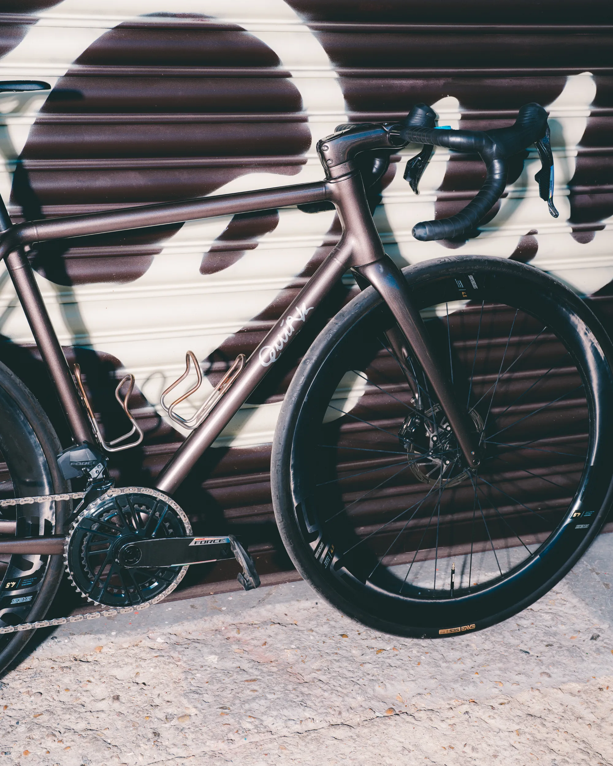 Light blue Quirk Cycles Durmitor road bike in a workshop with dark wheels