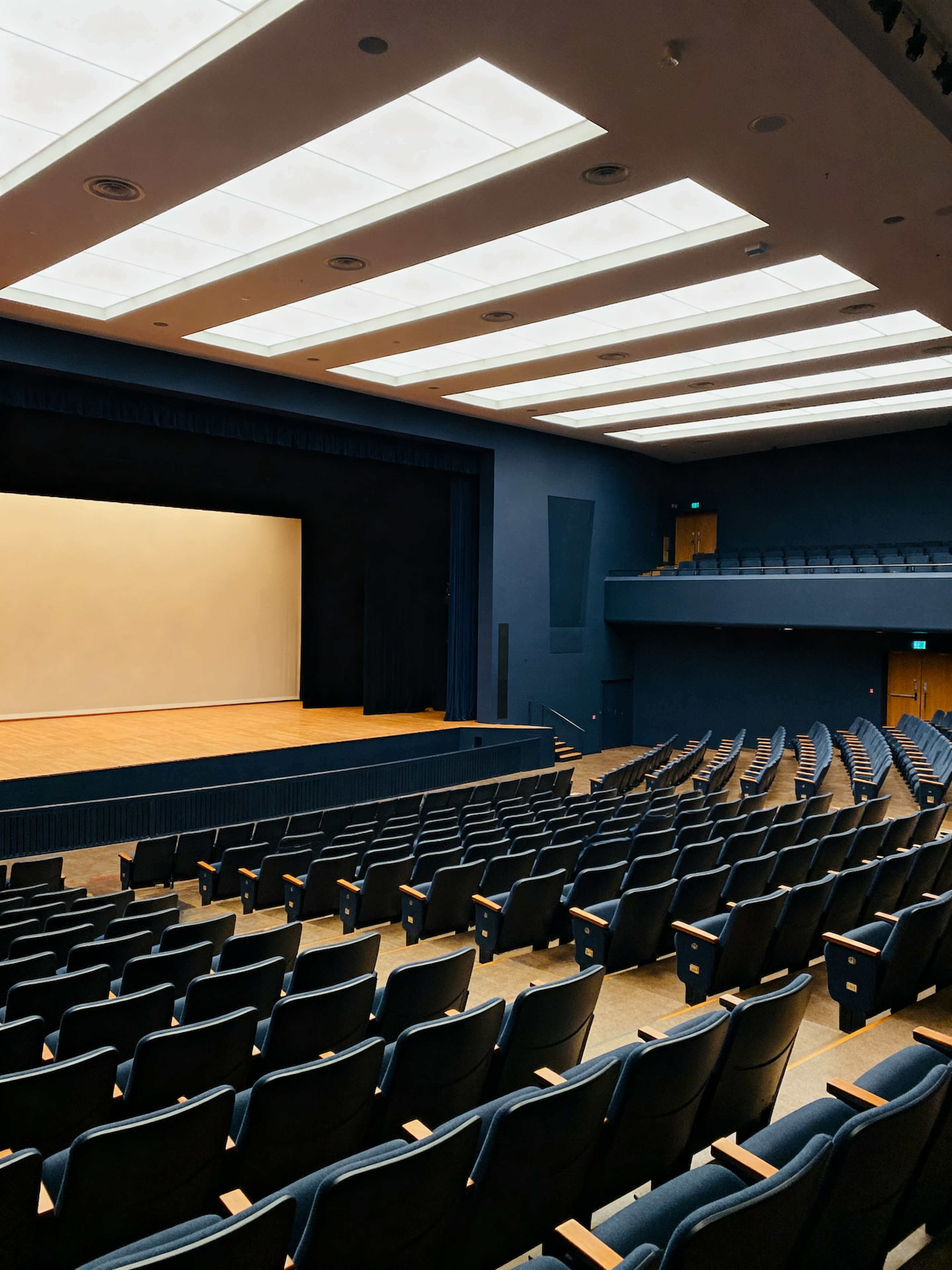 Auditório vazio com fileiras de cadeiras voltadas para um palco com iluminação, representando a realização da palestra.