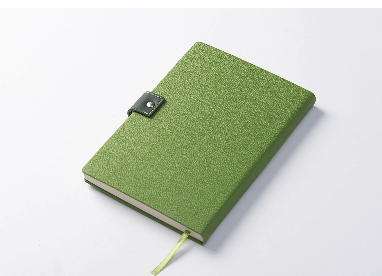 High-angle view of a closed lime green diary resting on a white surface, highlighting the textured cover and secure dark green loop closure.
