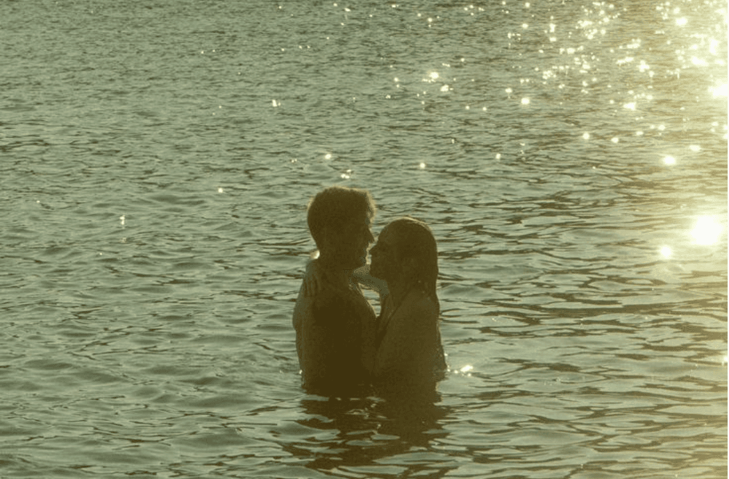 Two figures standing together in sunlit water