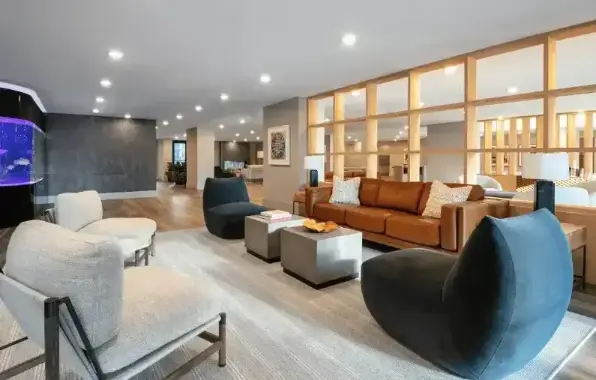 Modern living room with stylish furniture, soft lighting, and a cozy atmosphere. Large windows and decorative elements visible.