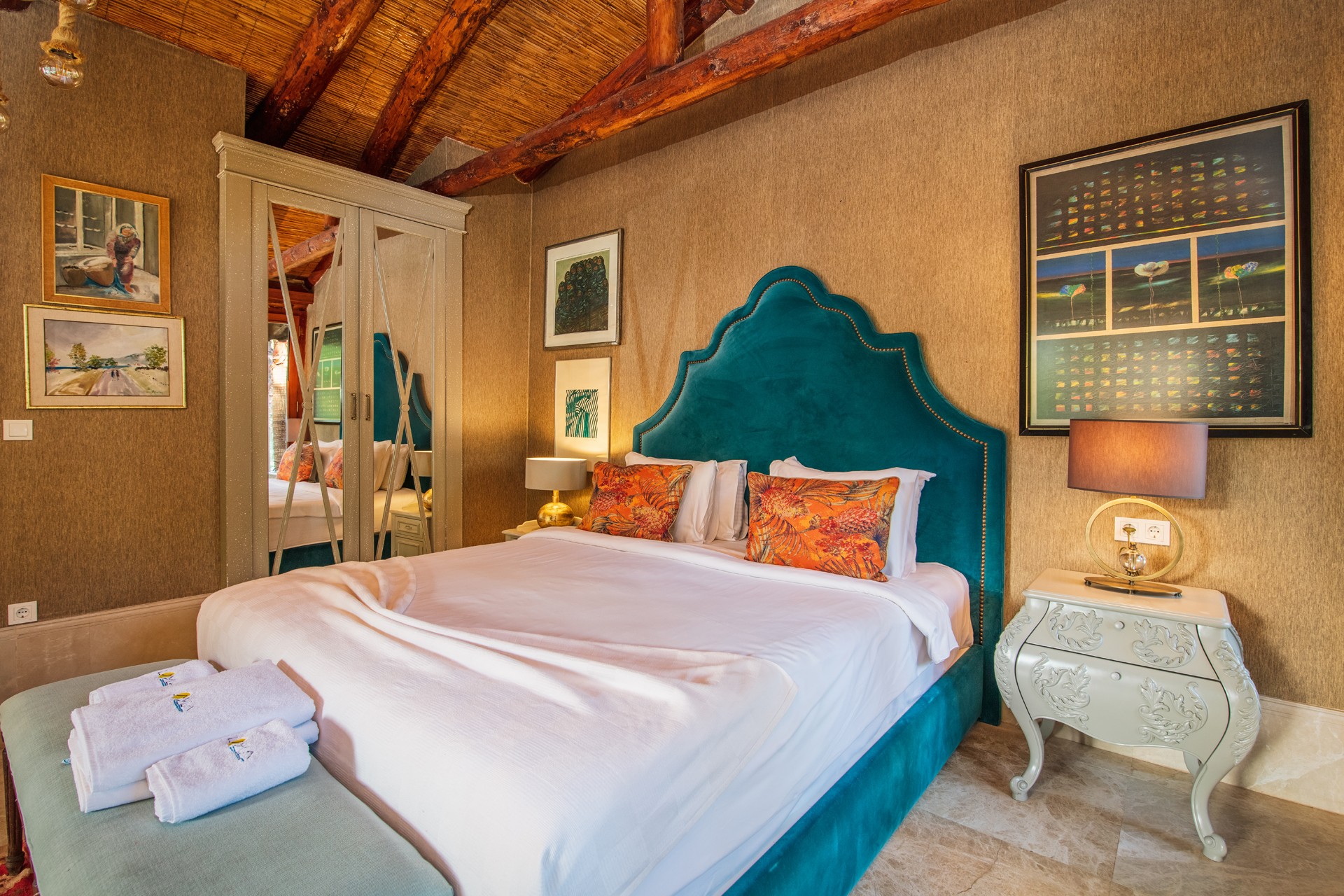 crisp white bedding, layered pillows, a plush bench at the foot of the bed
