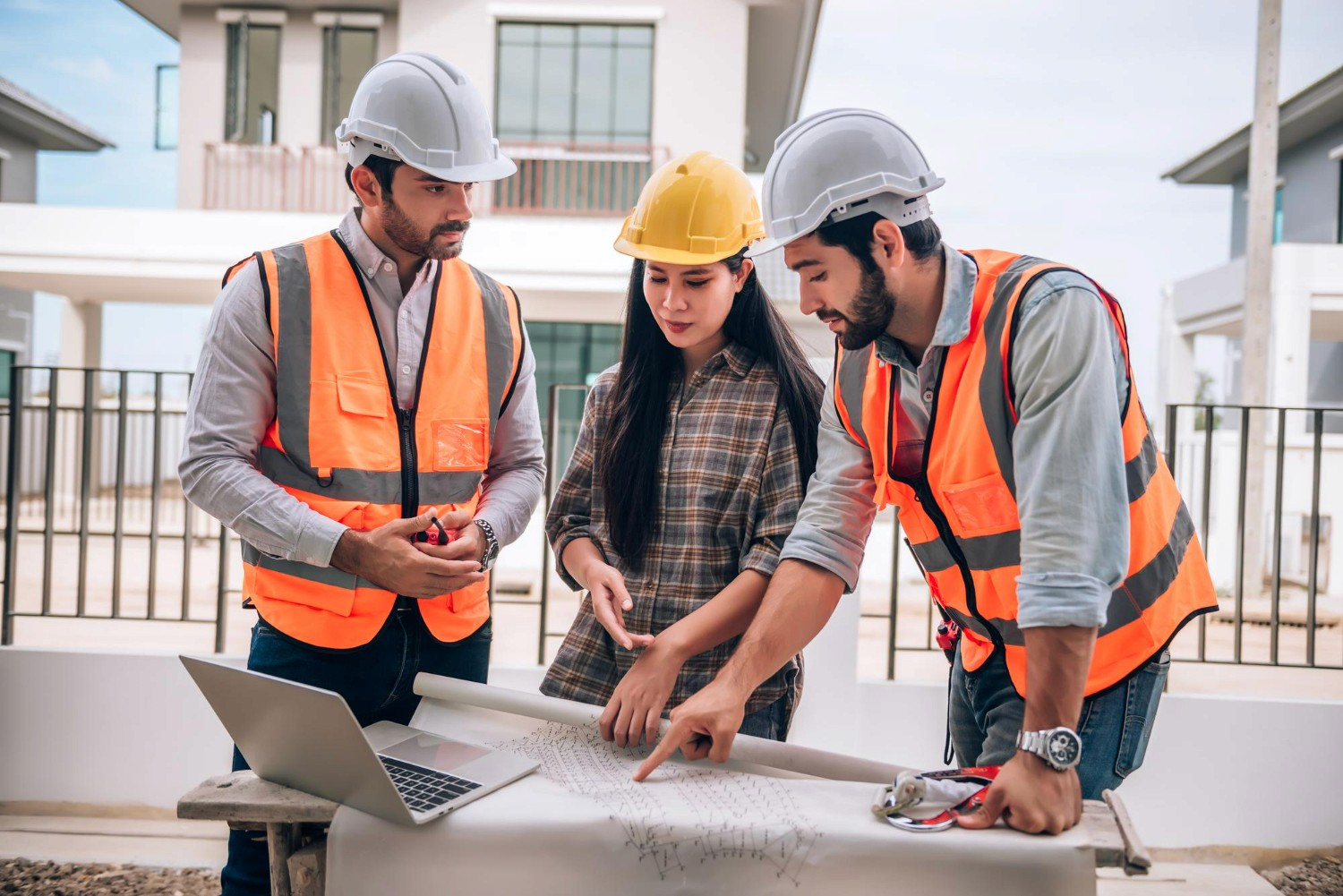 Profissionais da construção analisando os detalhes de uma reforma com notebook e planta