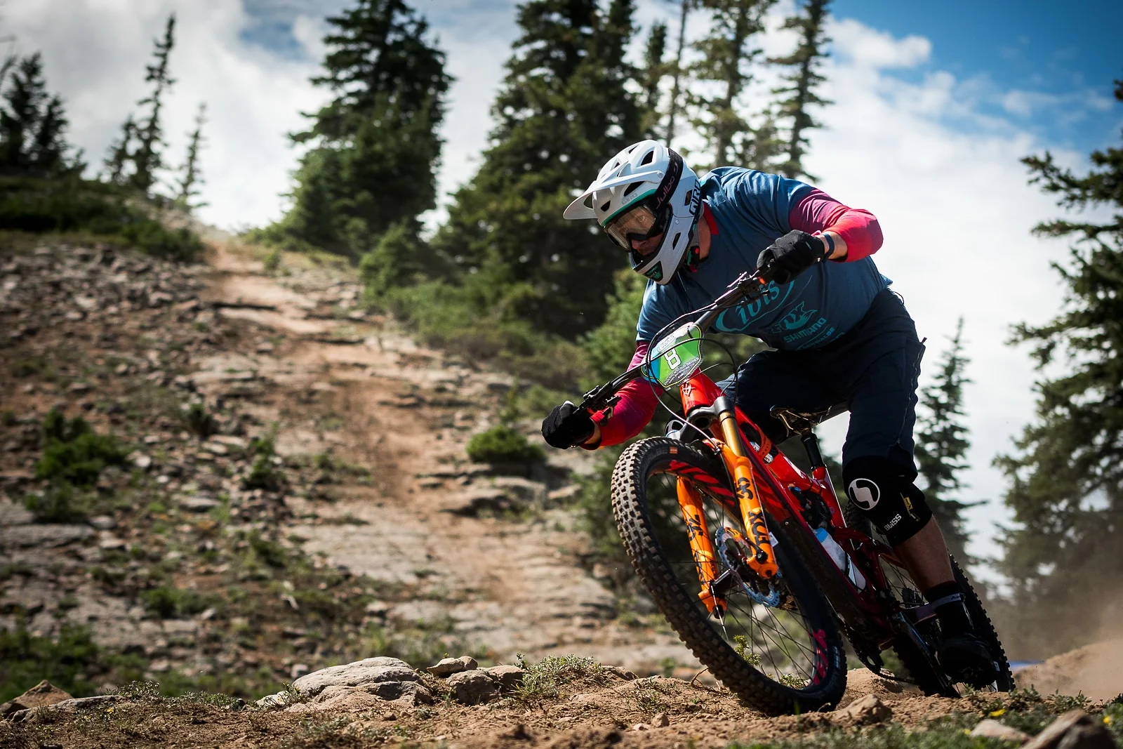 Coureur VTT en pleine descente sur un sentier de montagne pendant une compétition