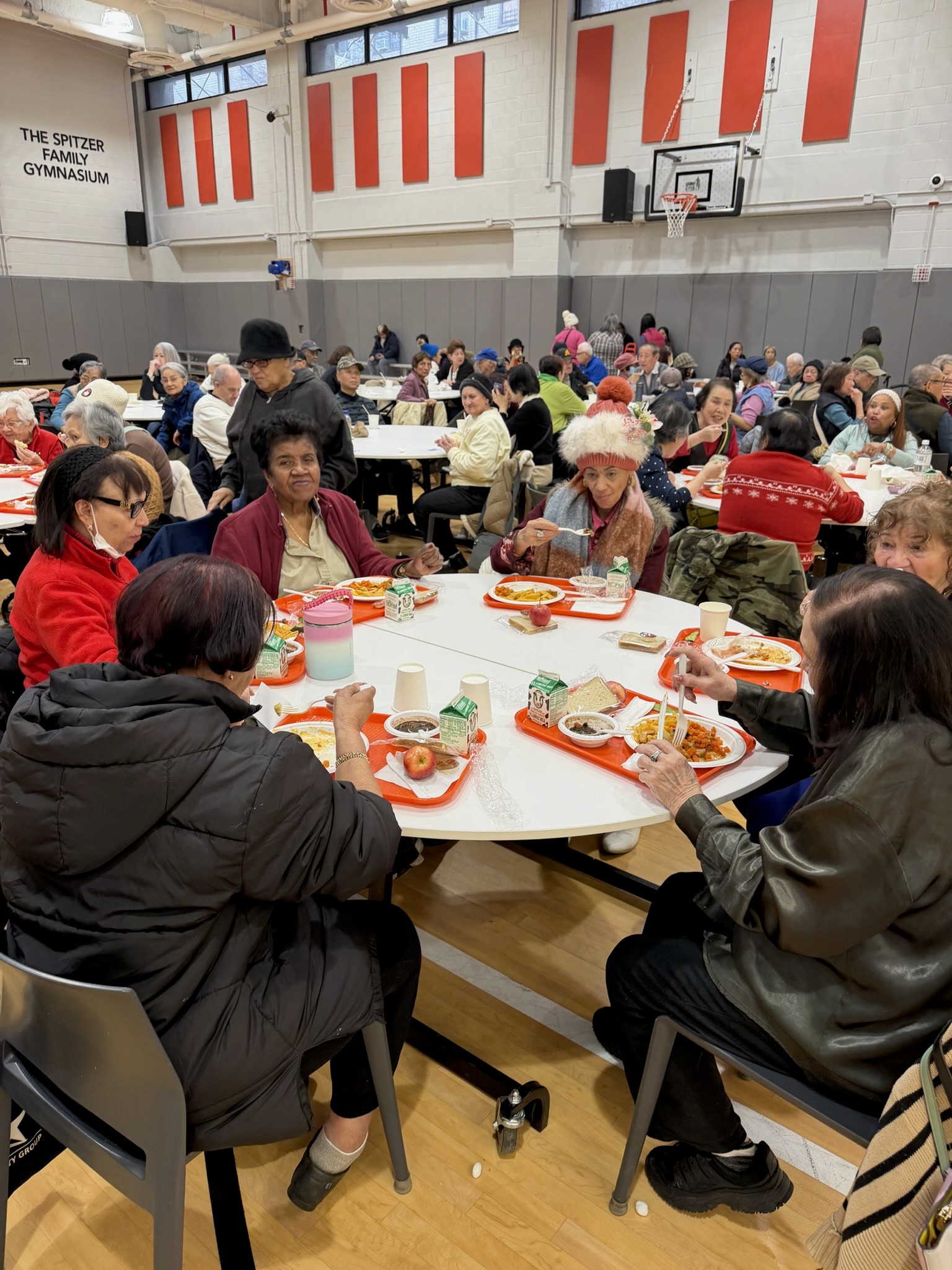 Two volunteers help an older woman store food from the pantry in her bag.