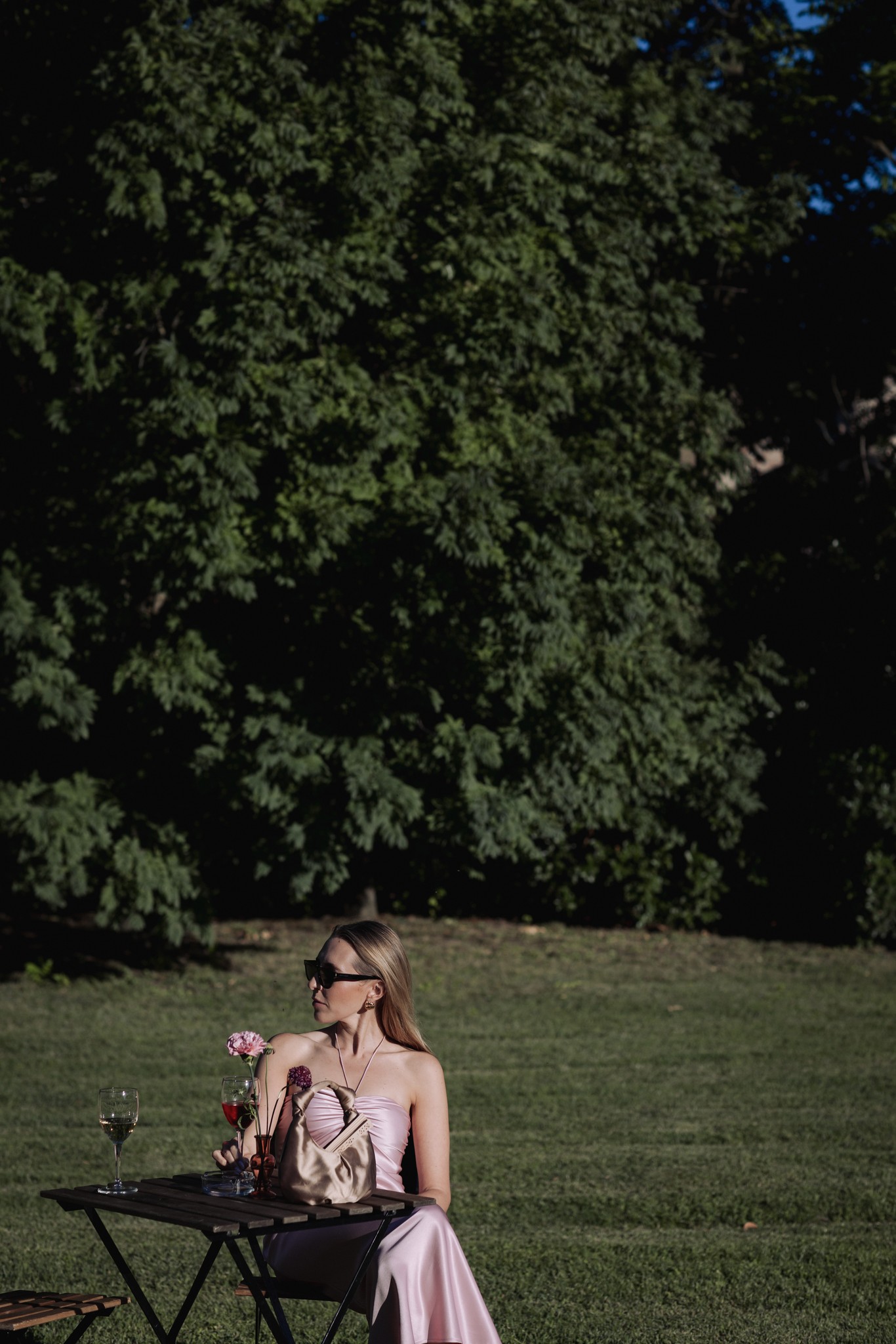 Sposa al Castello di Scipione seduta in abito rosa con bouquet, verde della vegetazione sullo sfondo, reportage matrimoniale