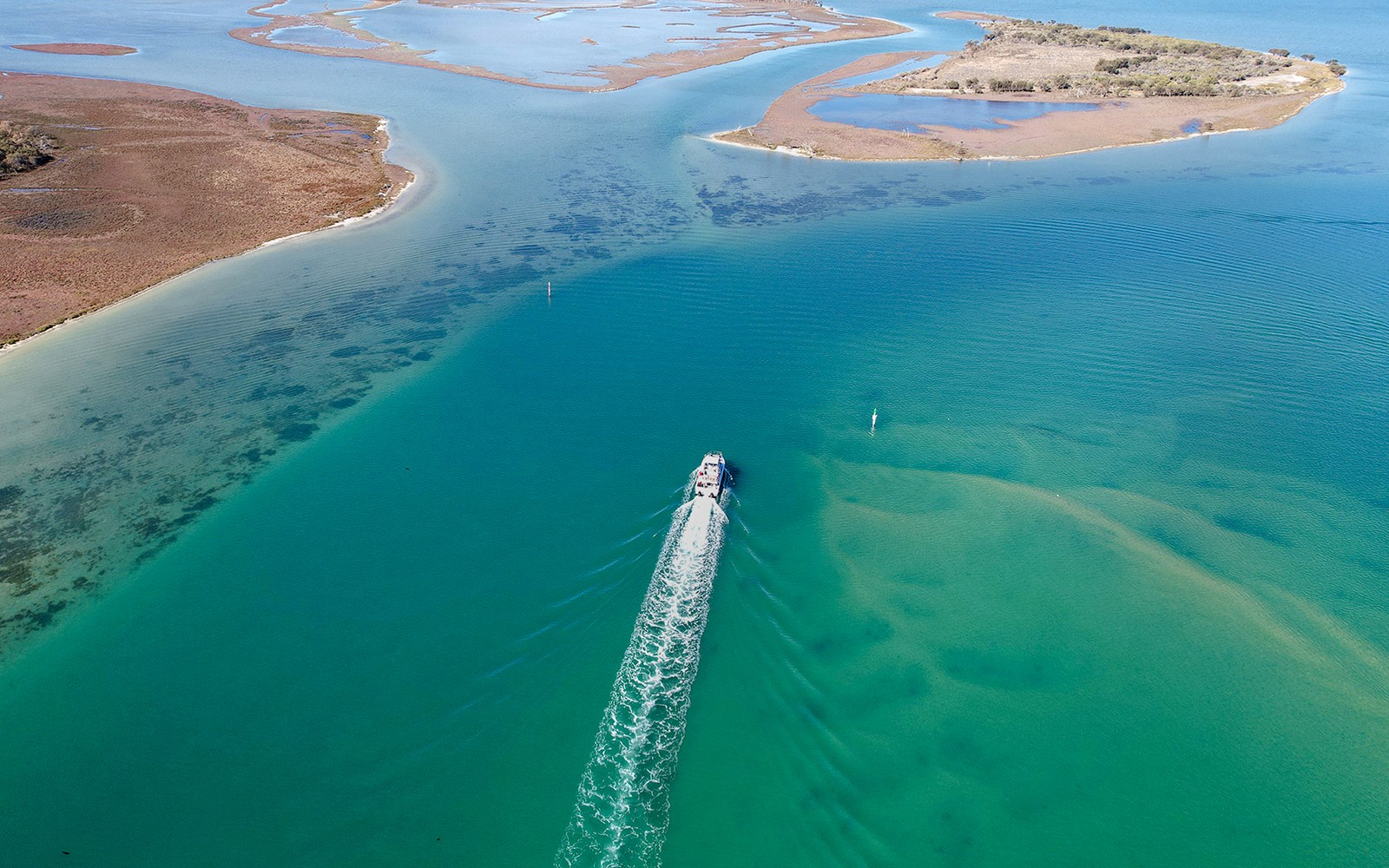 俯瞰一艘游轮在沿海岛屿附近的碧绿海水中航行的景象。