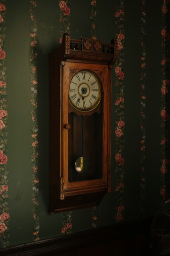 Antique pendulum clock on a floral wallpaper