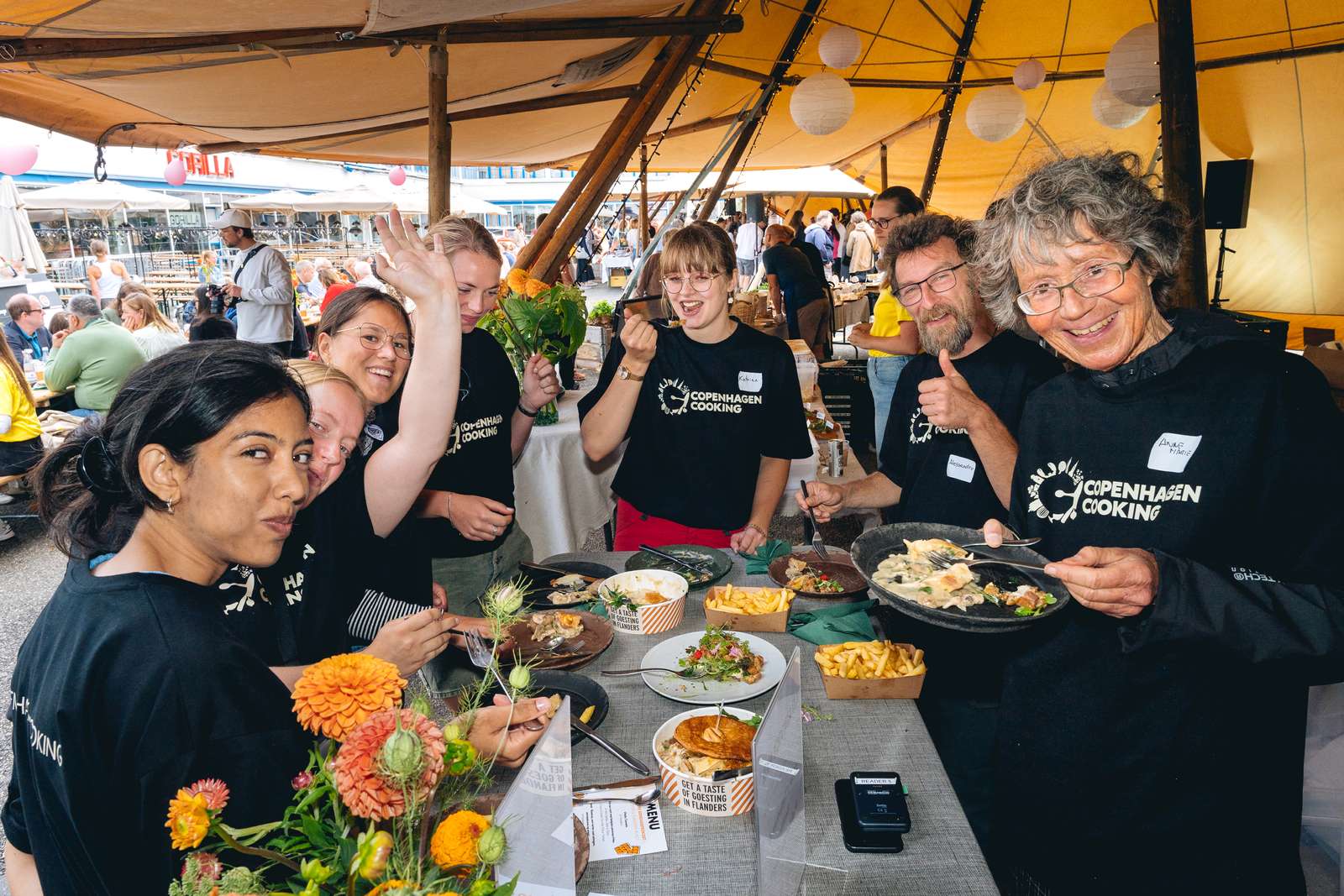 En gruppe af forskellige frivillige nyder en velfortjent frokost efter deres opgaver til Copenhagen Cooking i København