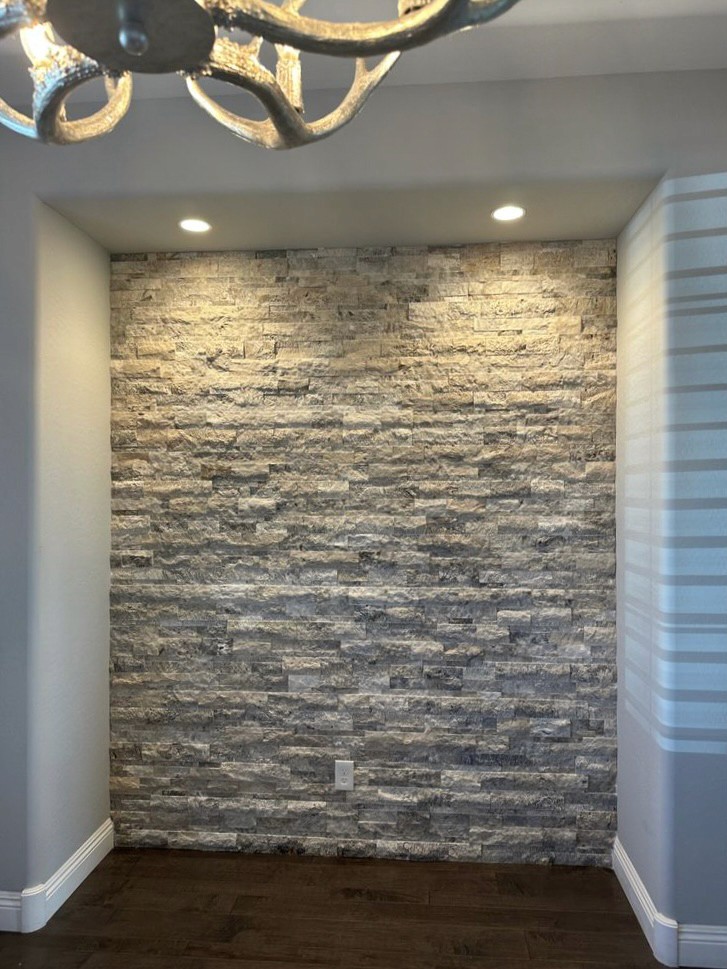 Stylish bathroom featuring a textured gray stone tile wall with recessed ceiling lights.