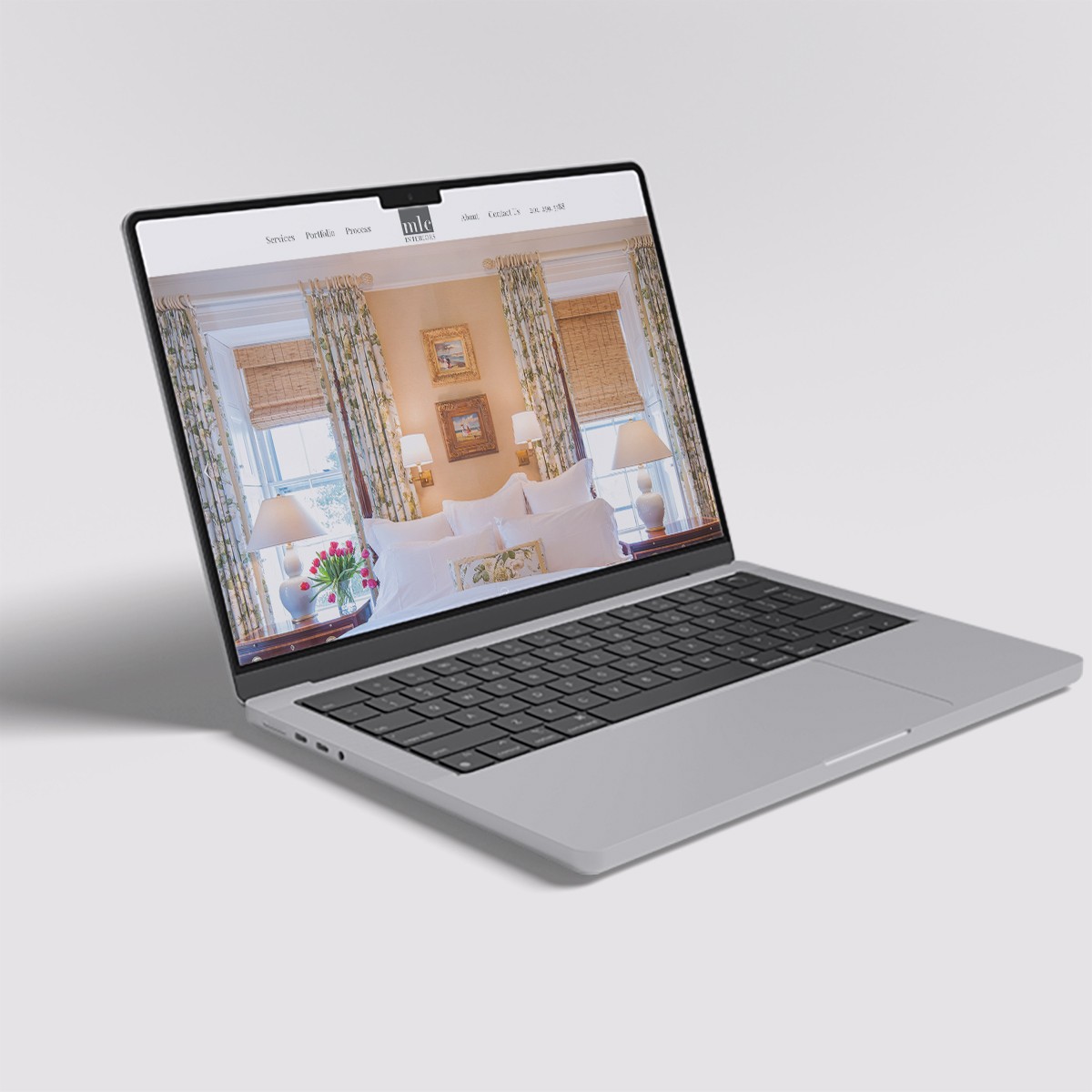Laptop displaying the MLC Interiors website featuring a bright, elegant bedroom design.