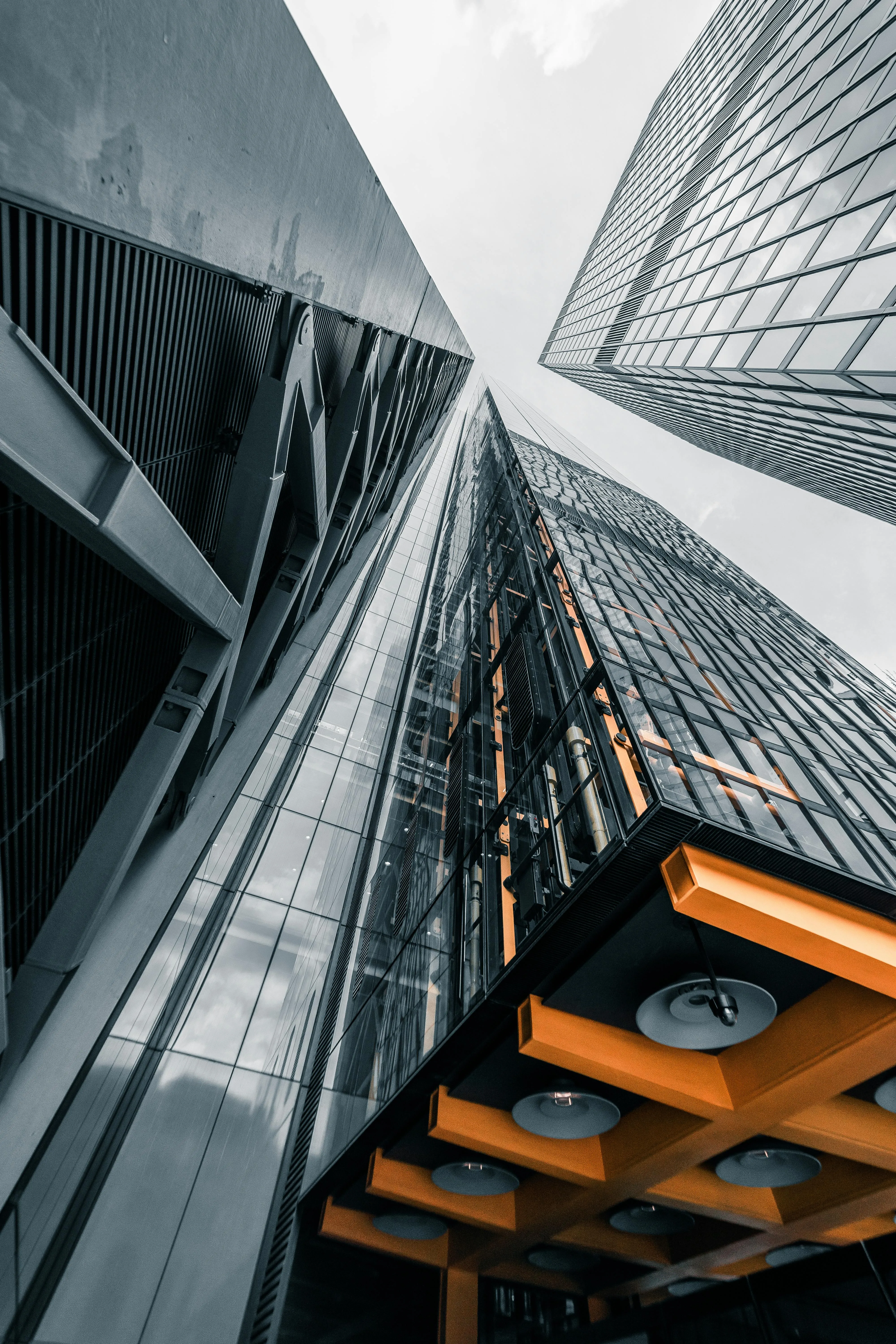 Low angle architectural view of a glass skyscraper reflecting geometric structural patterns and city light.