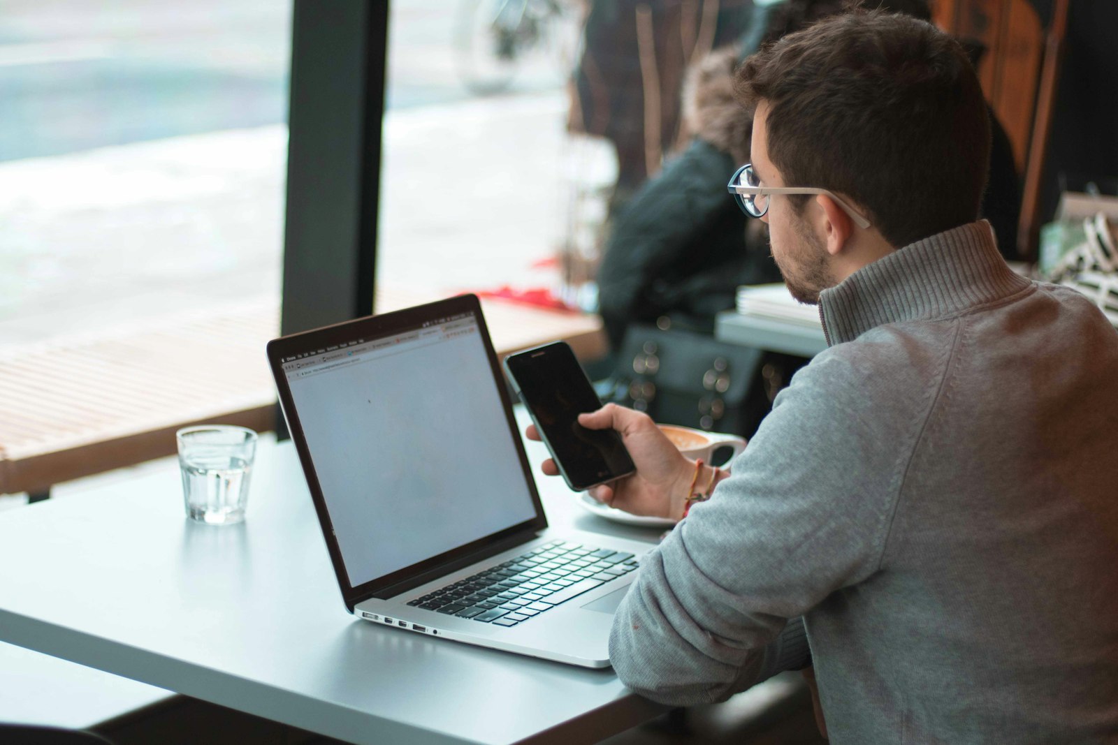 Verkoper aan een bureau met laptop en smartphone, klaar om een prospectielijst af te werken