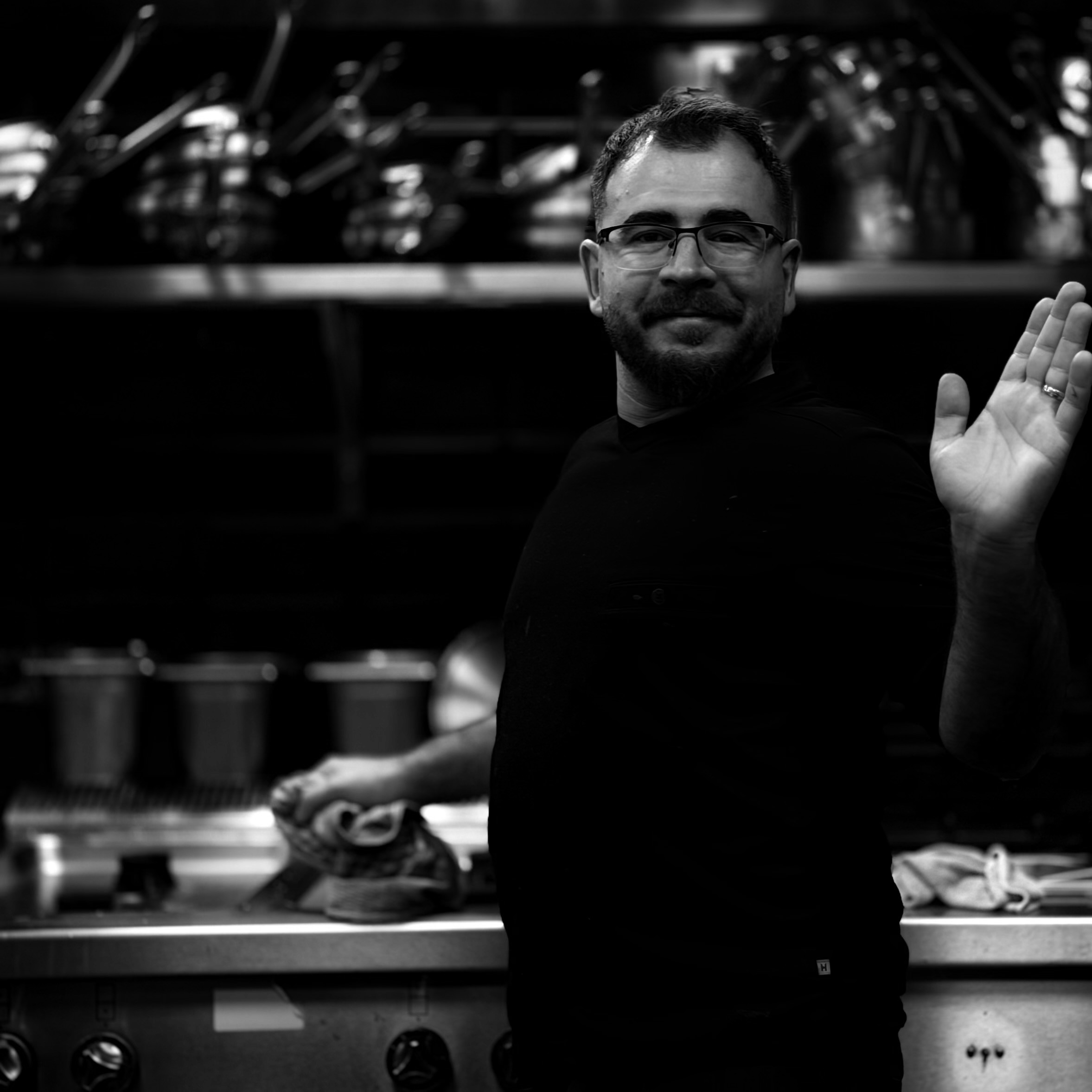 Friendly kitchen staff member waving from the kitchen at La Fontanella