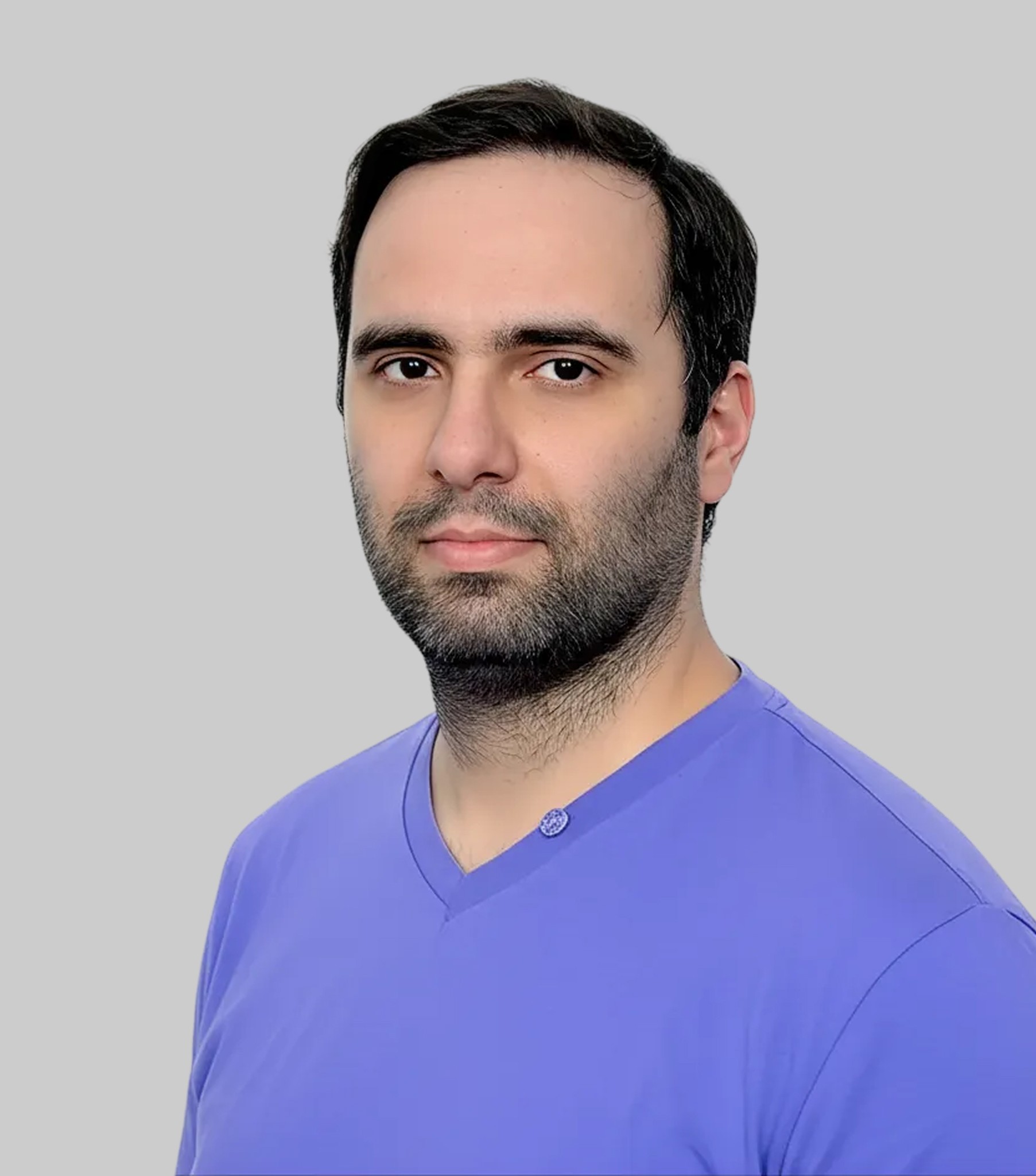 A woman with short curly hair wearing a black t-shirt looks into the camera.