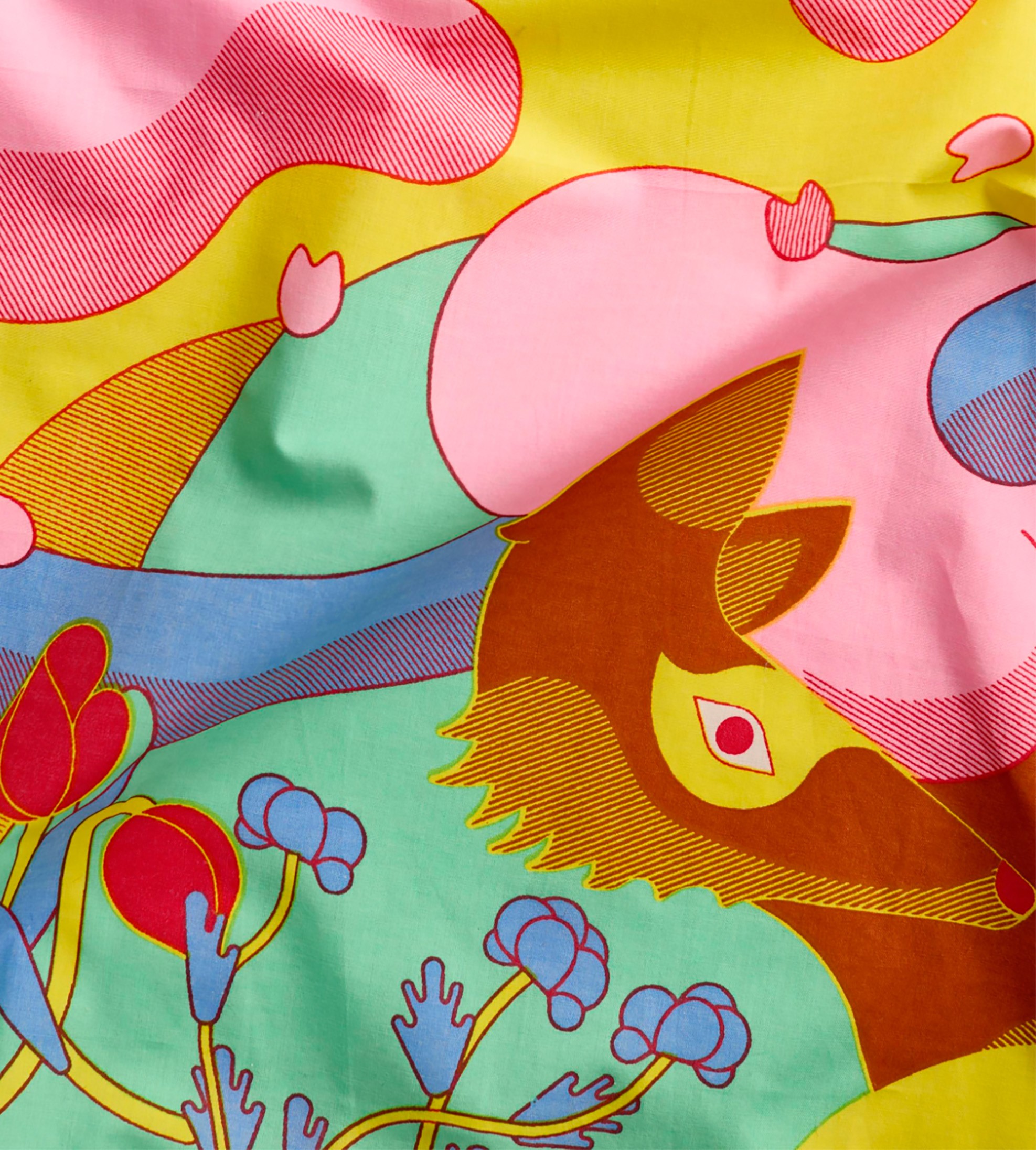 Close-up of an illustrated fabric showing a fox motif surrounded by flowing pastel shapes and floral details.