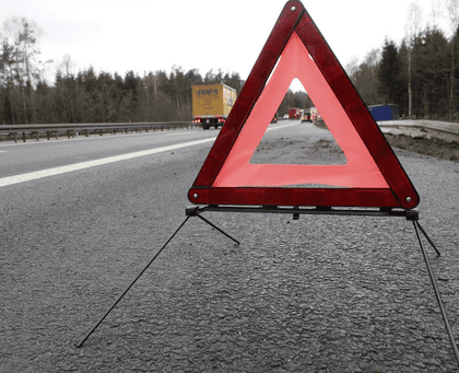 Warning triangle on a highway near a commercial truck, representing accident response and insurance claims support for truckers.