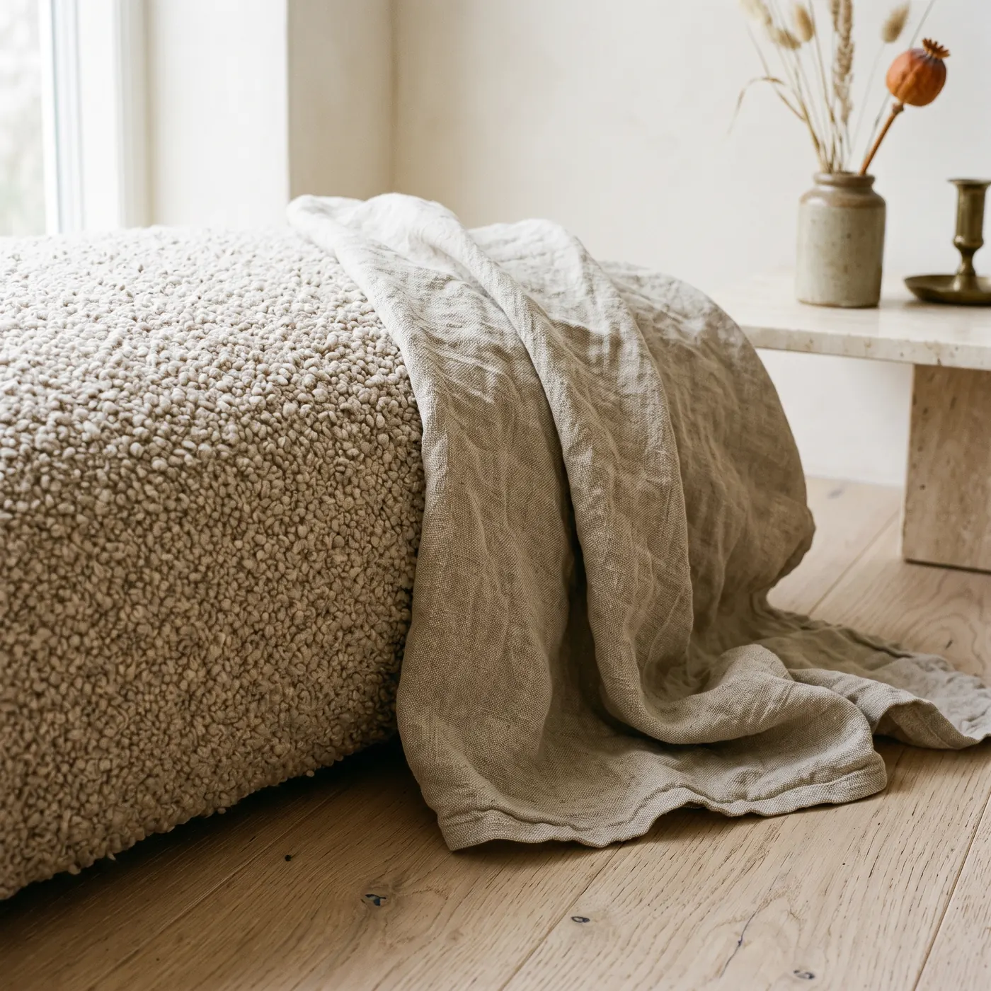 A boucle throw folded on a wooden bench in soft light