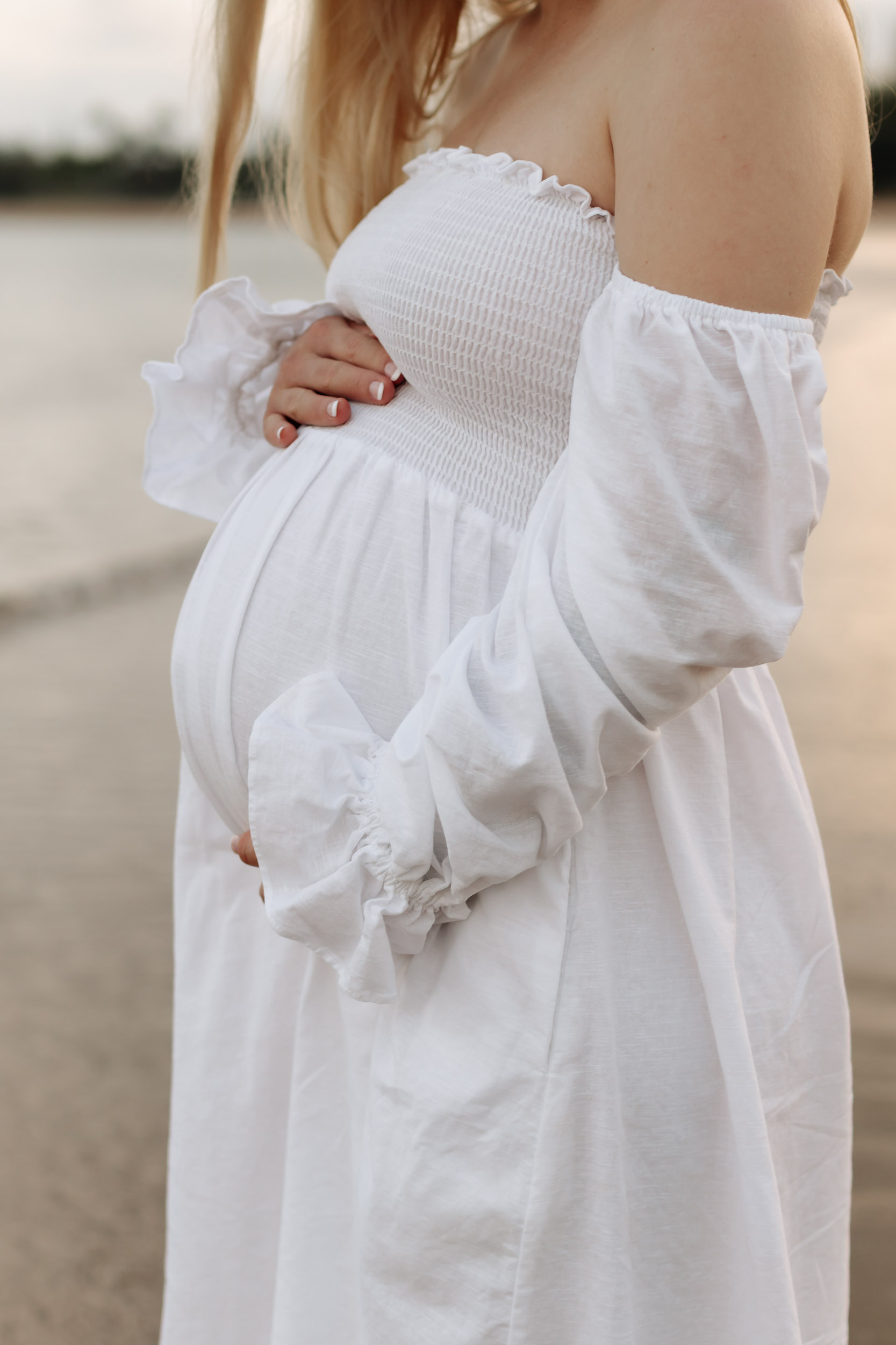 Solo maternity portrait of an expecting mother at Mackay beach with warm evening light reflecting on the water