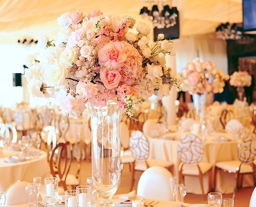 Elegant wedding decor featuring soft floral arrangements and beautifully set tables under a warm-toned canopy.