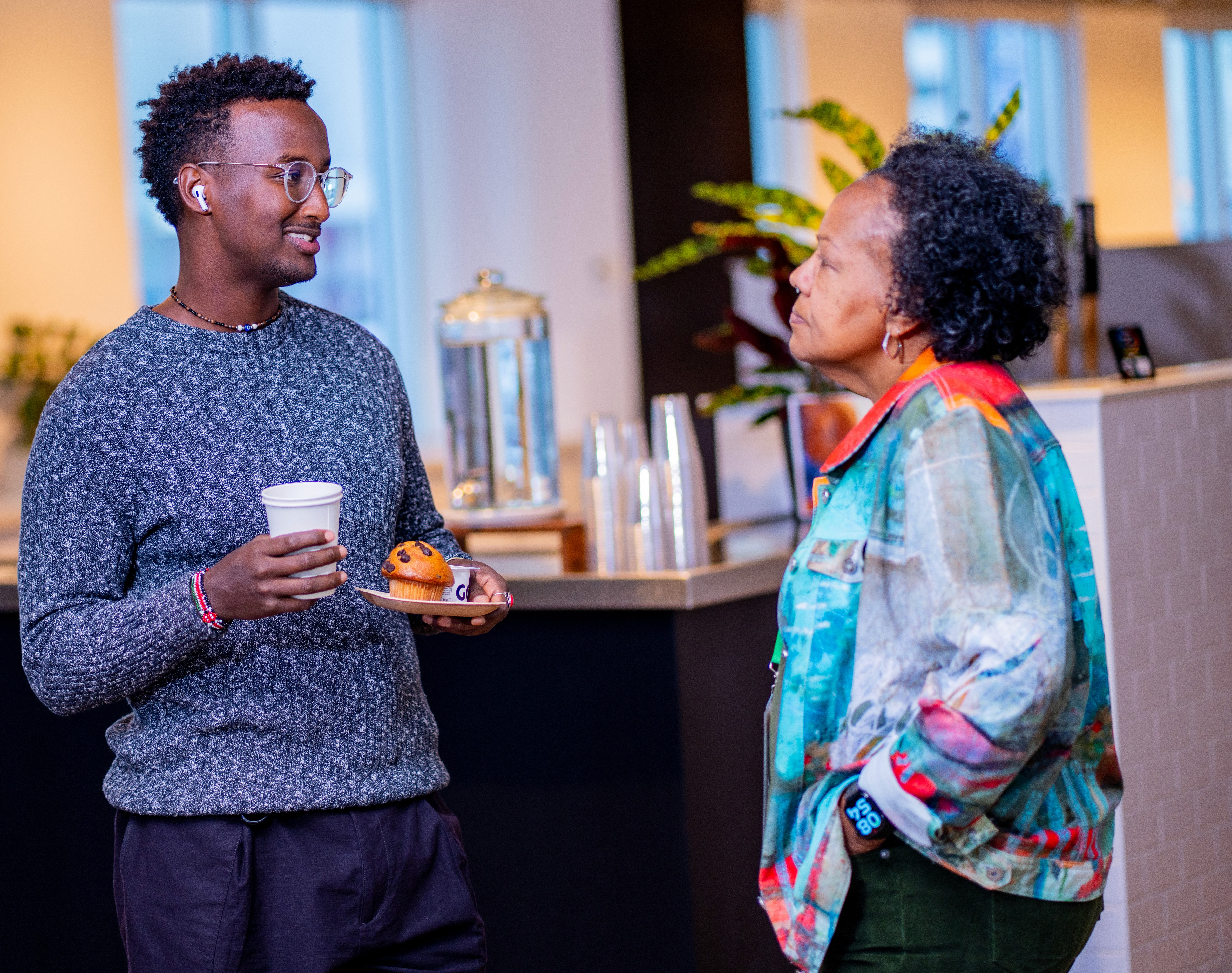 A group of people standing at a podium, smiling and applauding, with a large window in the background.