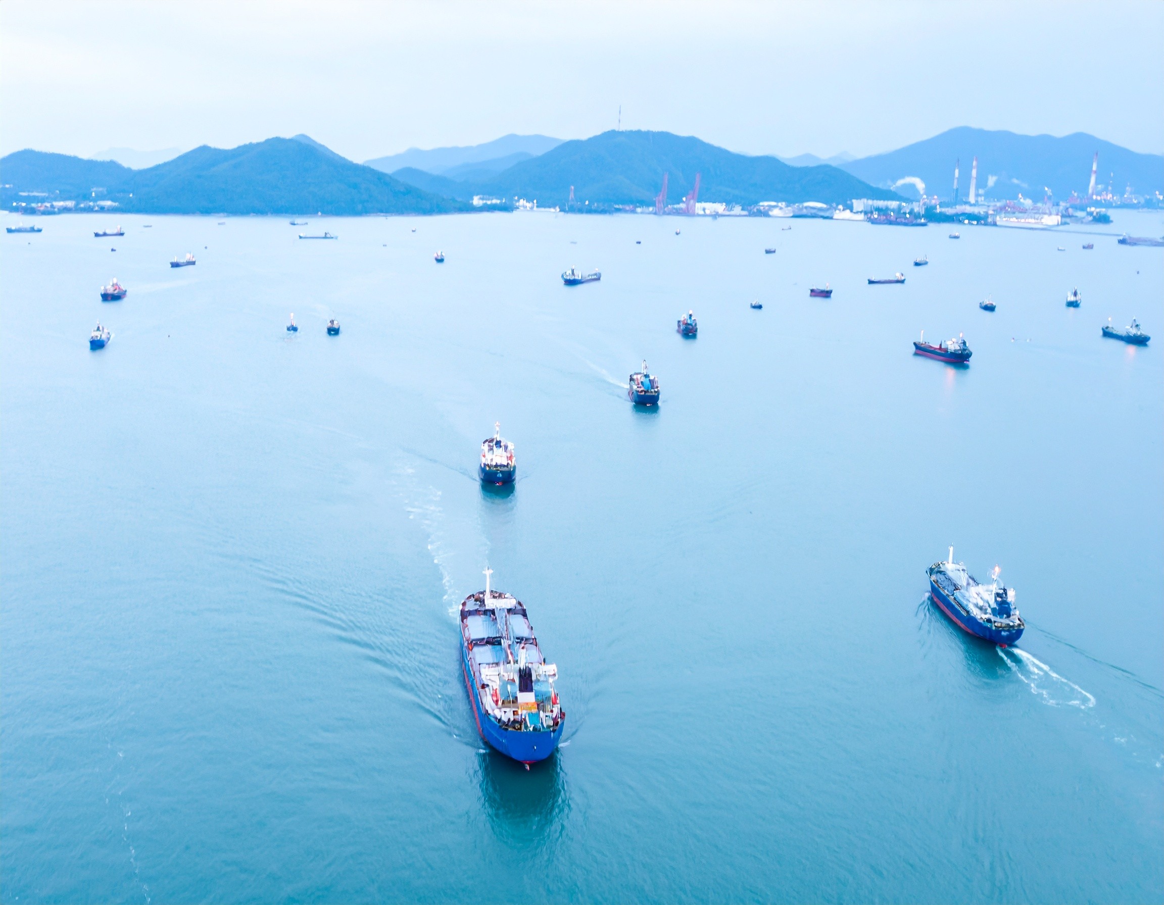 fleet of ships at sea with coast in background