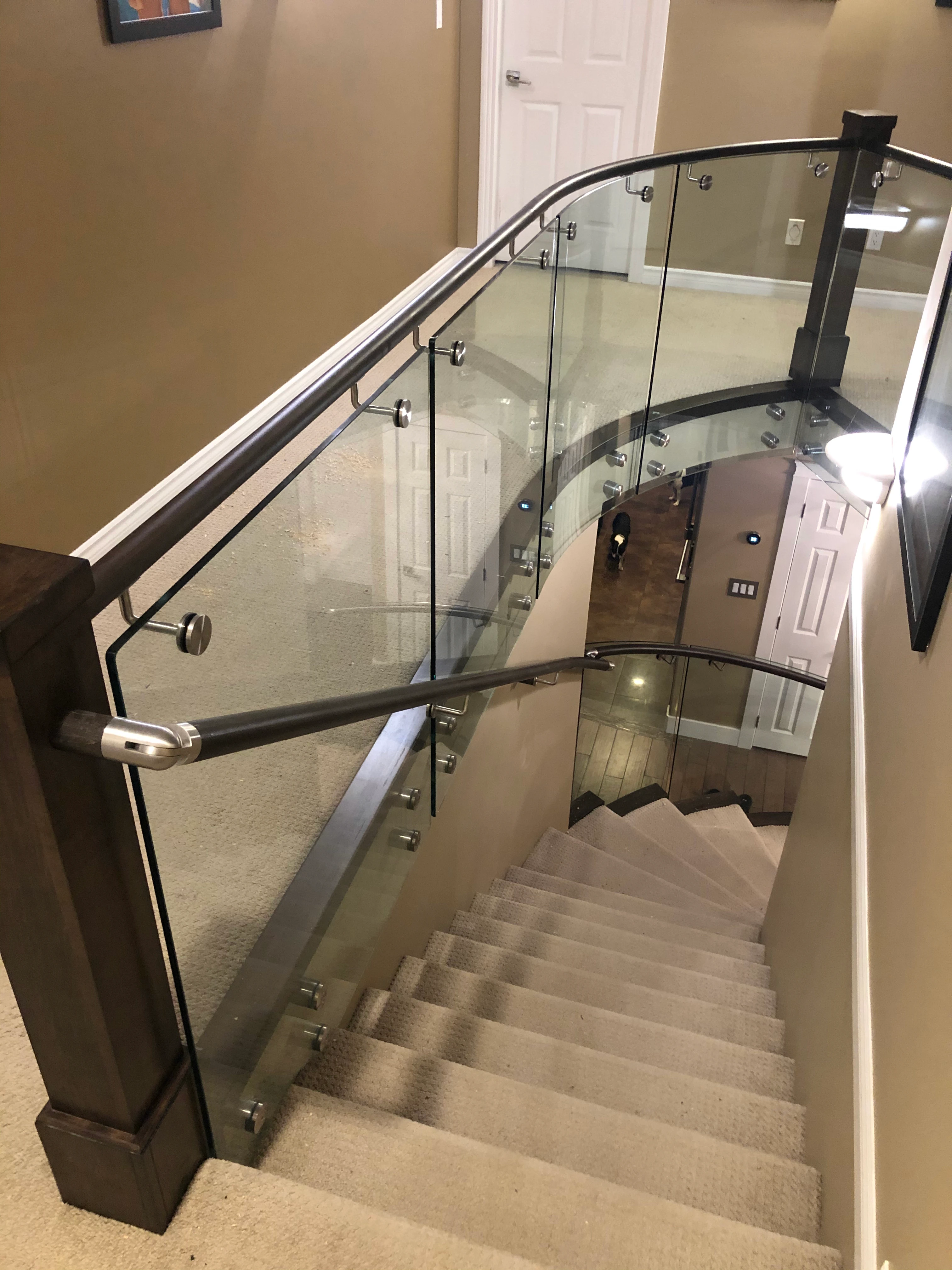 Curved glass stair railing mounted with stainless steel standoffs