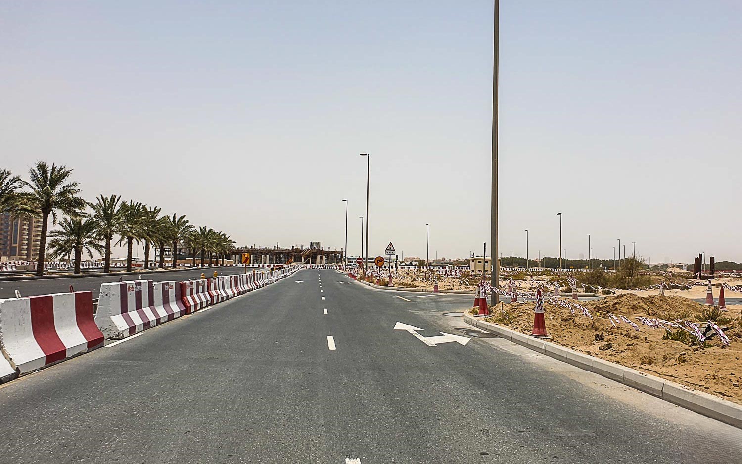 Street-level view of parked cars and modern mid-rise apartments in the Dubailand Residence Complex.