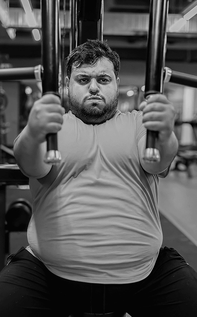 Man working out on a chest press machine during the early stage of his fitness journey, aiming to lose body fat.