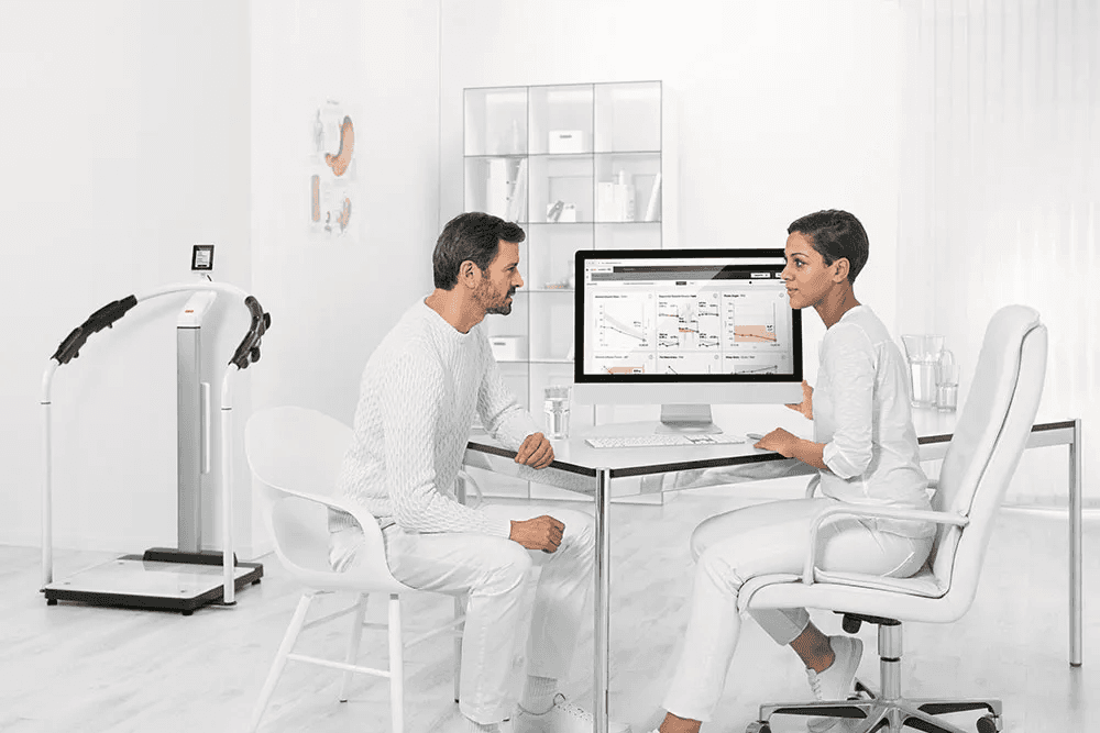Two people sitting in a futuristic office, by a computer.