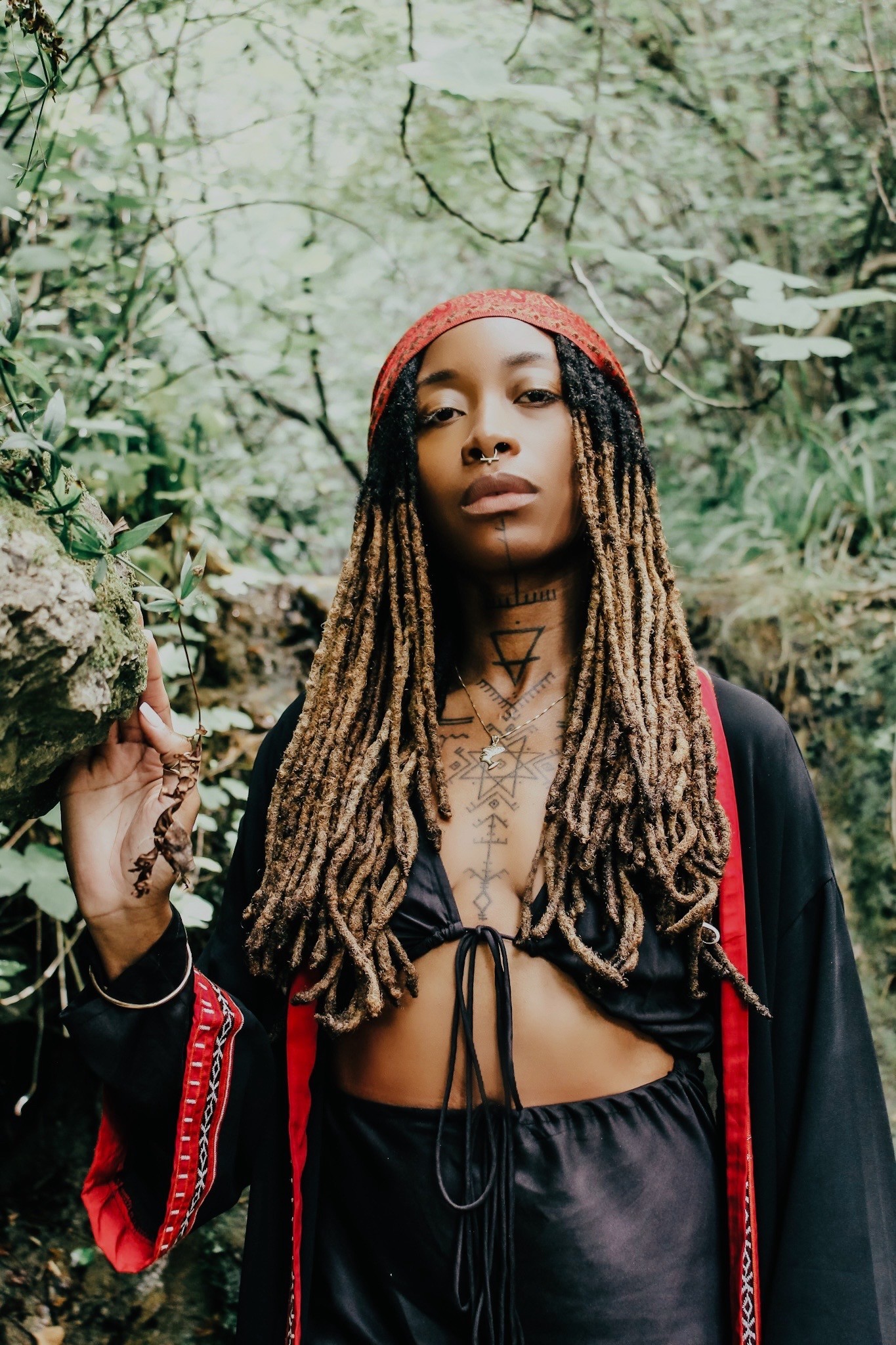 A baker's hands skillfully knead a large ball of dough on a rustic wooden table, with a stone wall and window providing a warm, natural light in the background.