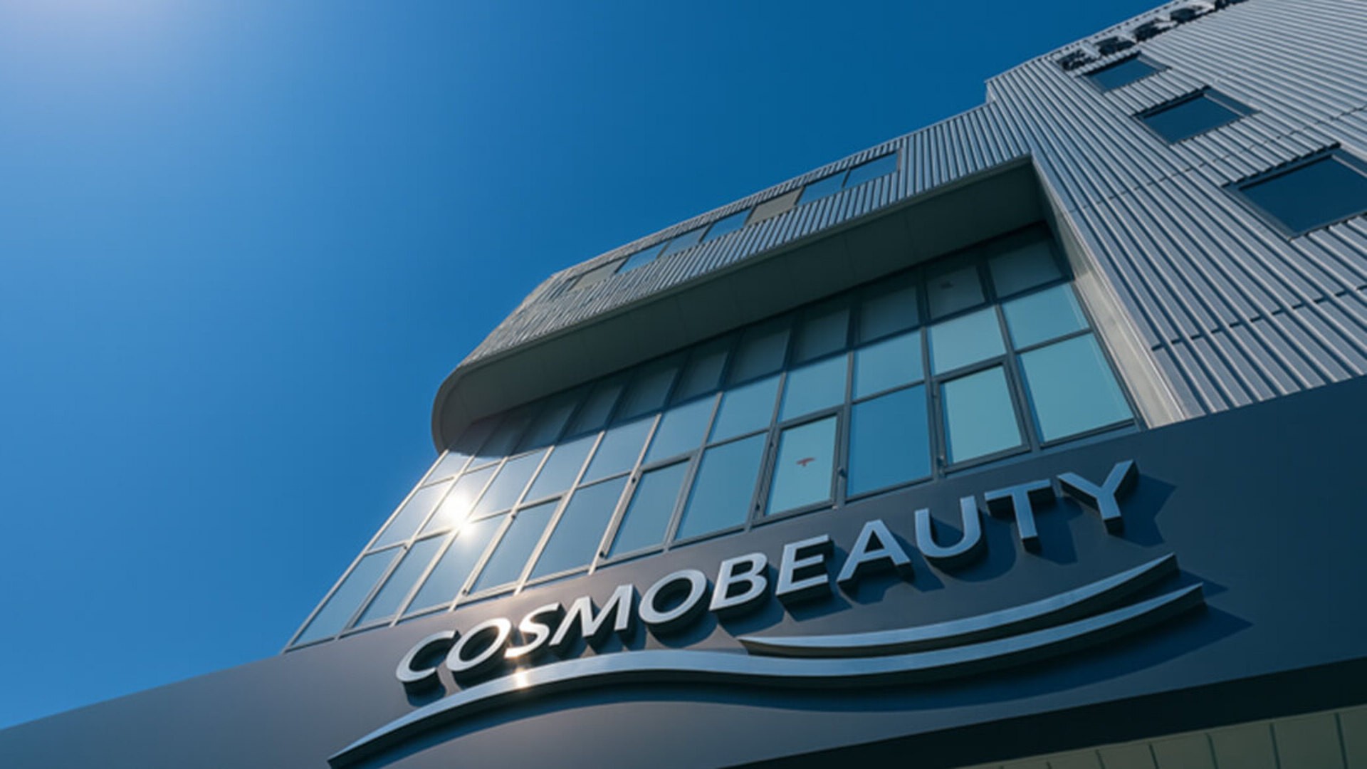 青空を背景にした株式会社コスモビューティーの社屋ビル外観