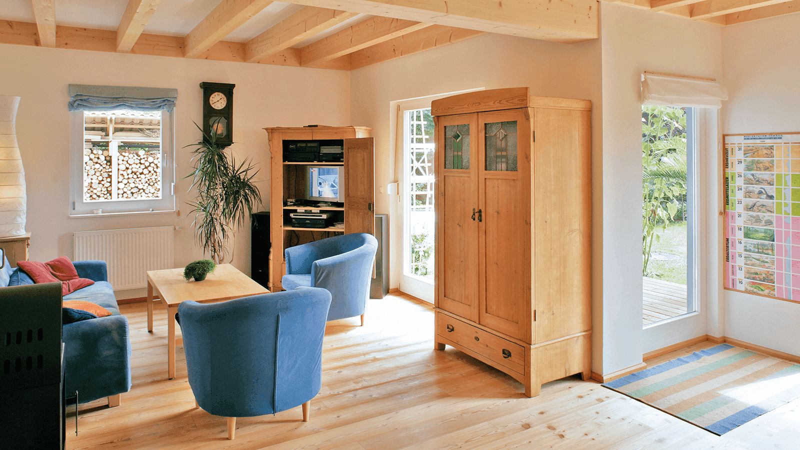 Gemütliches Wohnzimmer mit Holzmöbeln, blauen Sitzmöbeln und einem Holzboden.
