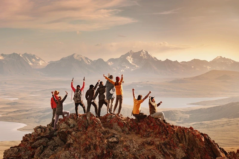 team celebrating on a mountain summit overlooking a valley
