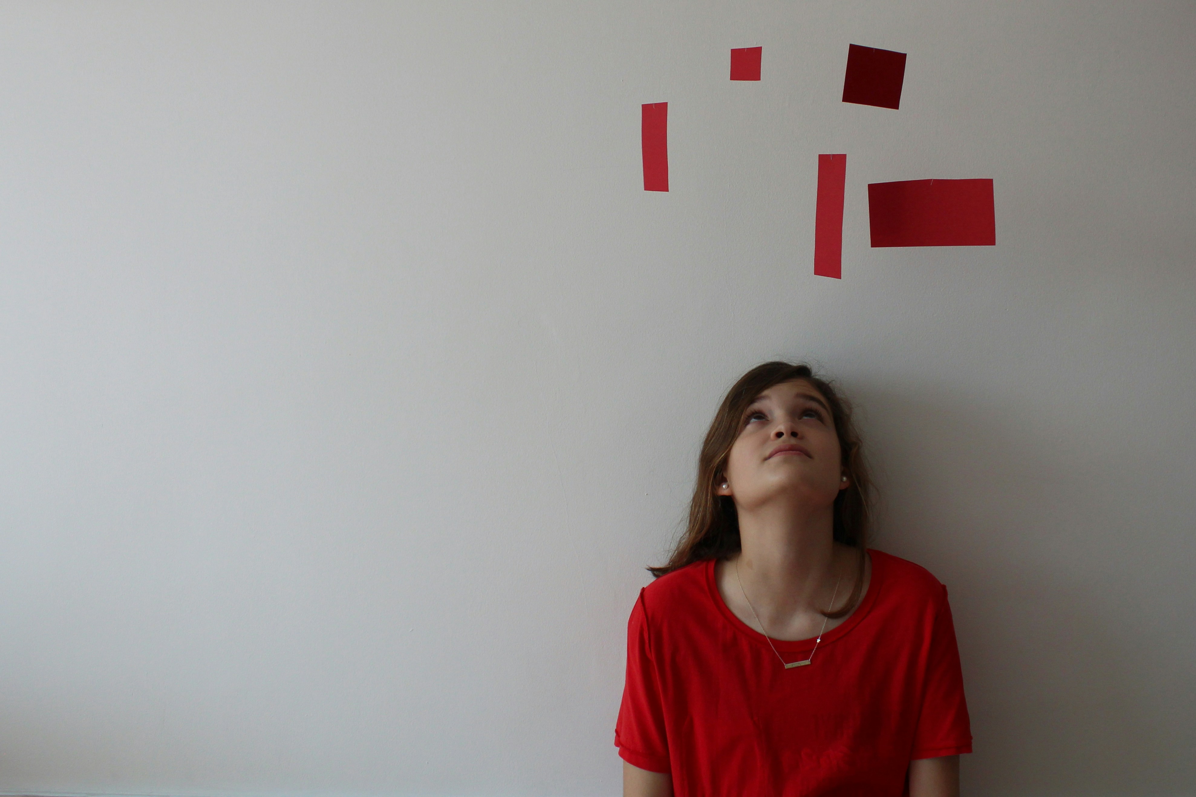 Person gazing upward at red paper shapes representing thinking through hypothetical situational interview scenarios