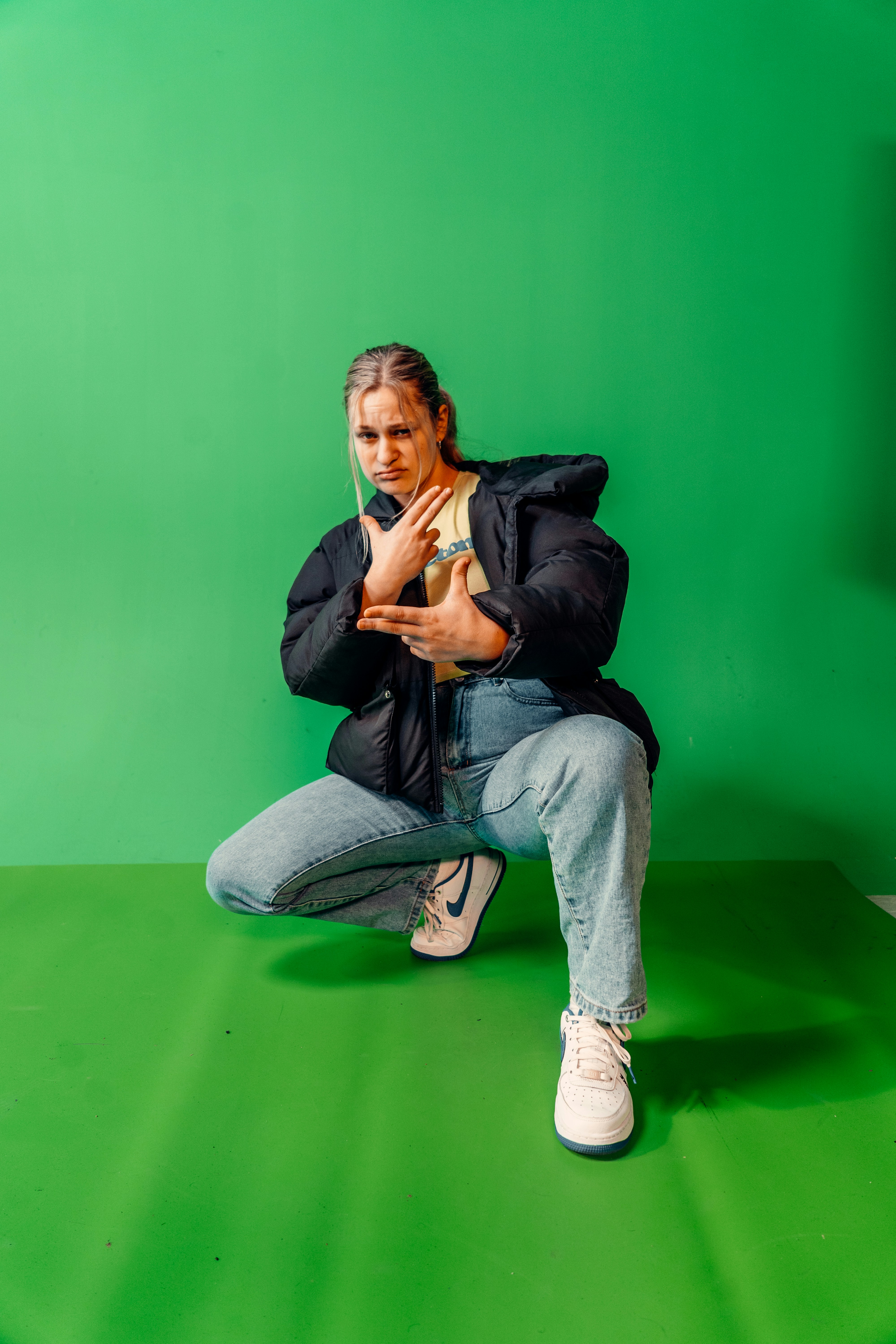 a woman kneeling down in front of a green background