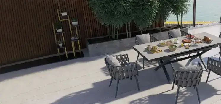 Modern grey outdoor dining set with rope armchairs on a luxury patio overlooking water